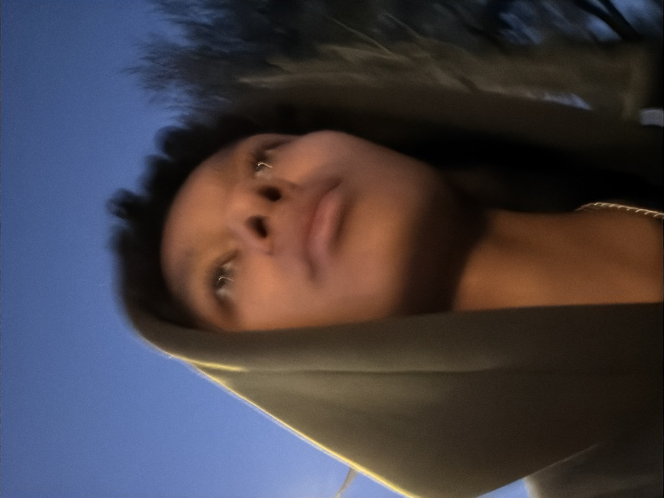Young person in hoodie photographed against blue sky