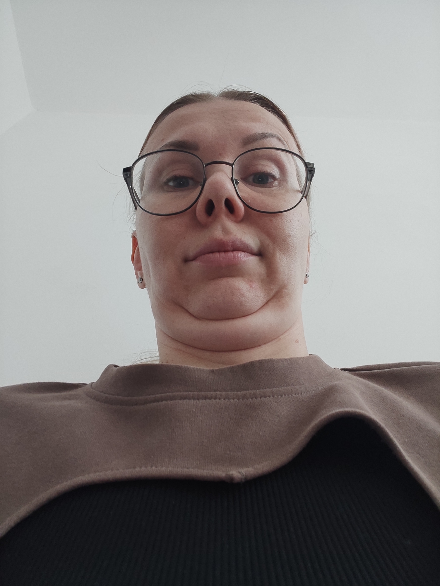 Woman in brown sweatshirt photographed indoors against white background