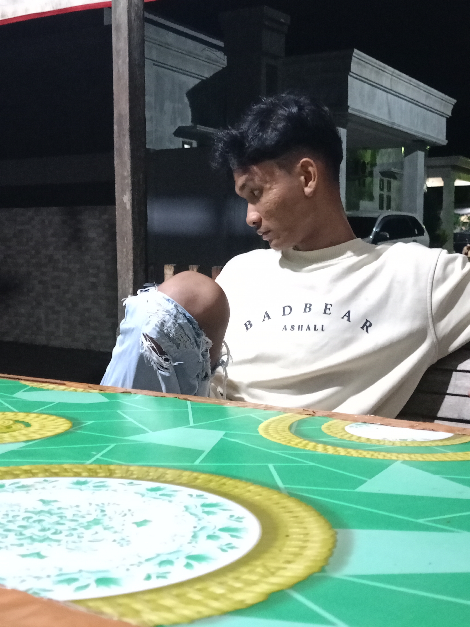 Man sits outdoors at night table in Lhokseumawe