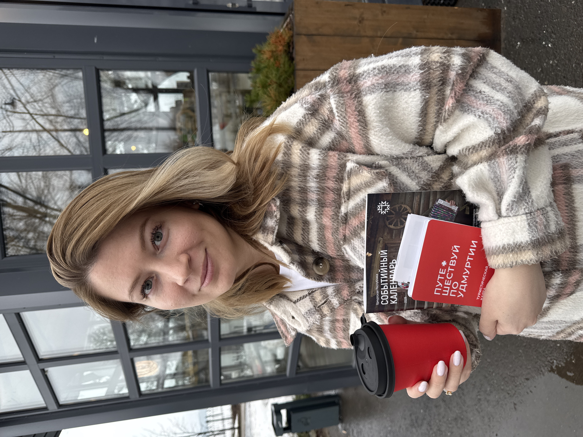 Woman reviews Udmurtia tourism materials outside Votkinsk cafe
