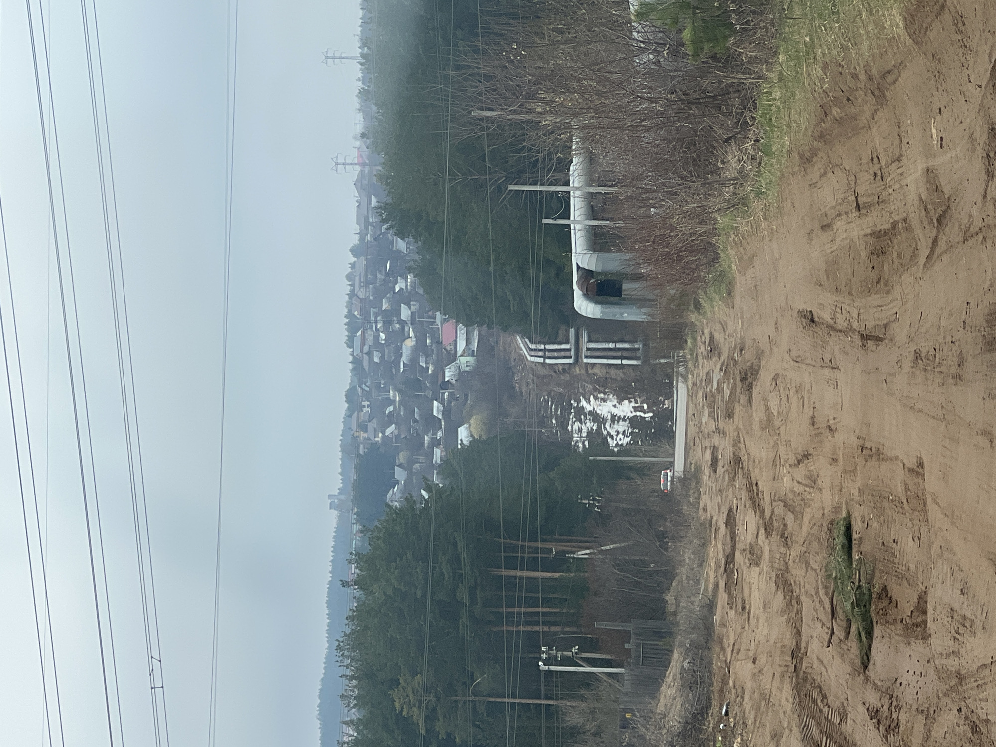 Tractor operation observed in rural Chaikovsky amid industrial landscape