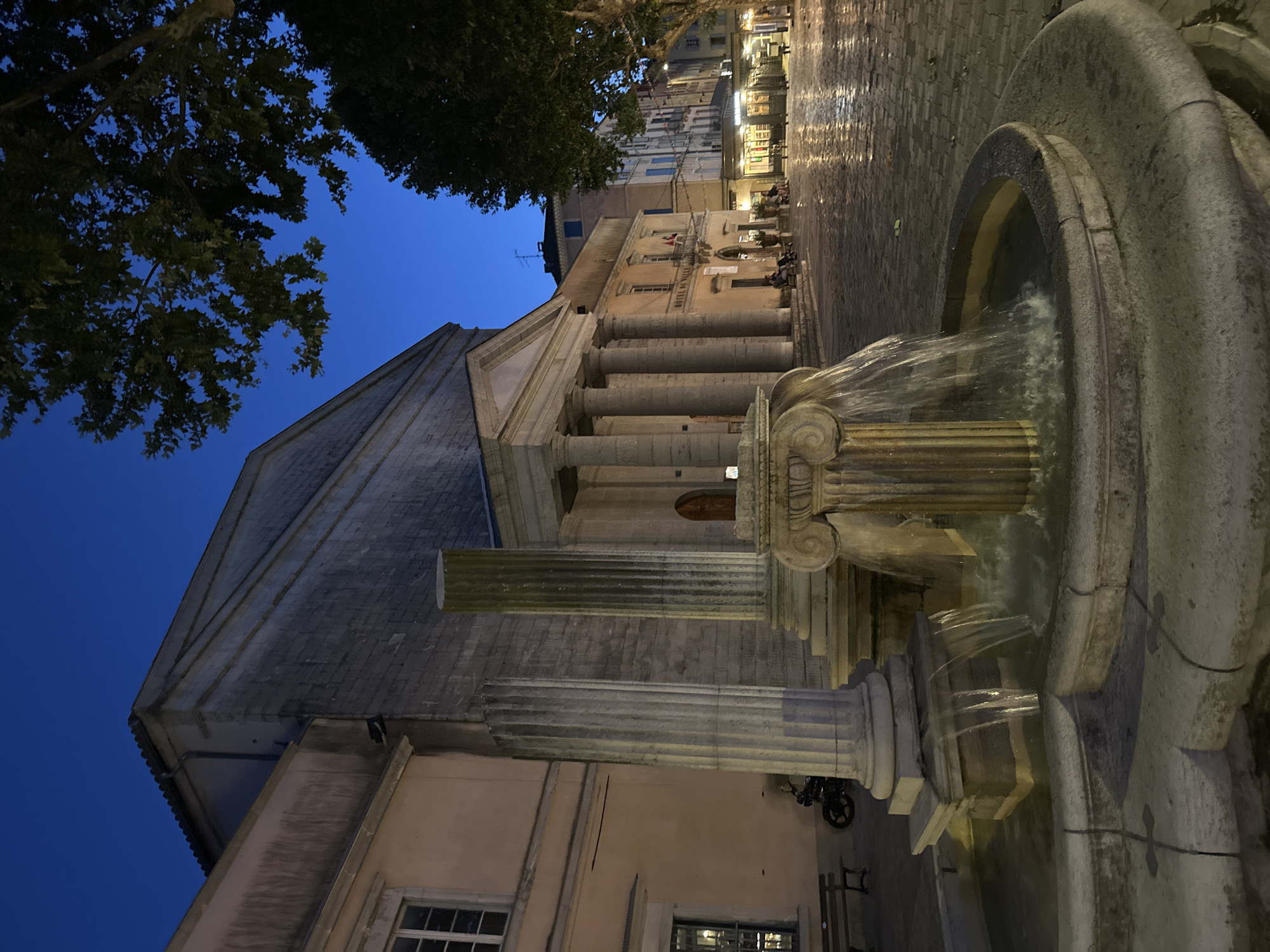 Anduze at twilight: fountain, clock tower, and lit streets