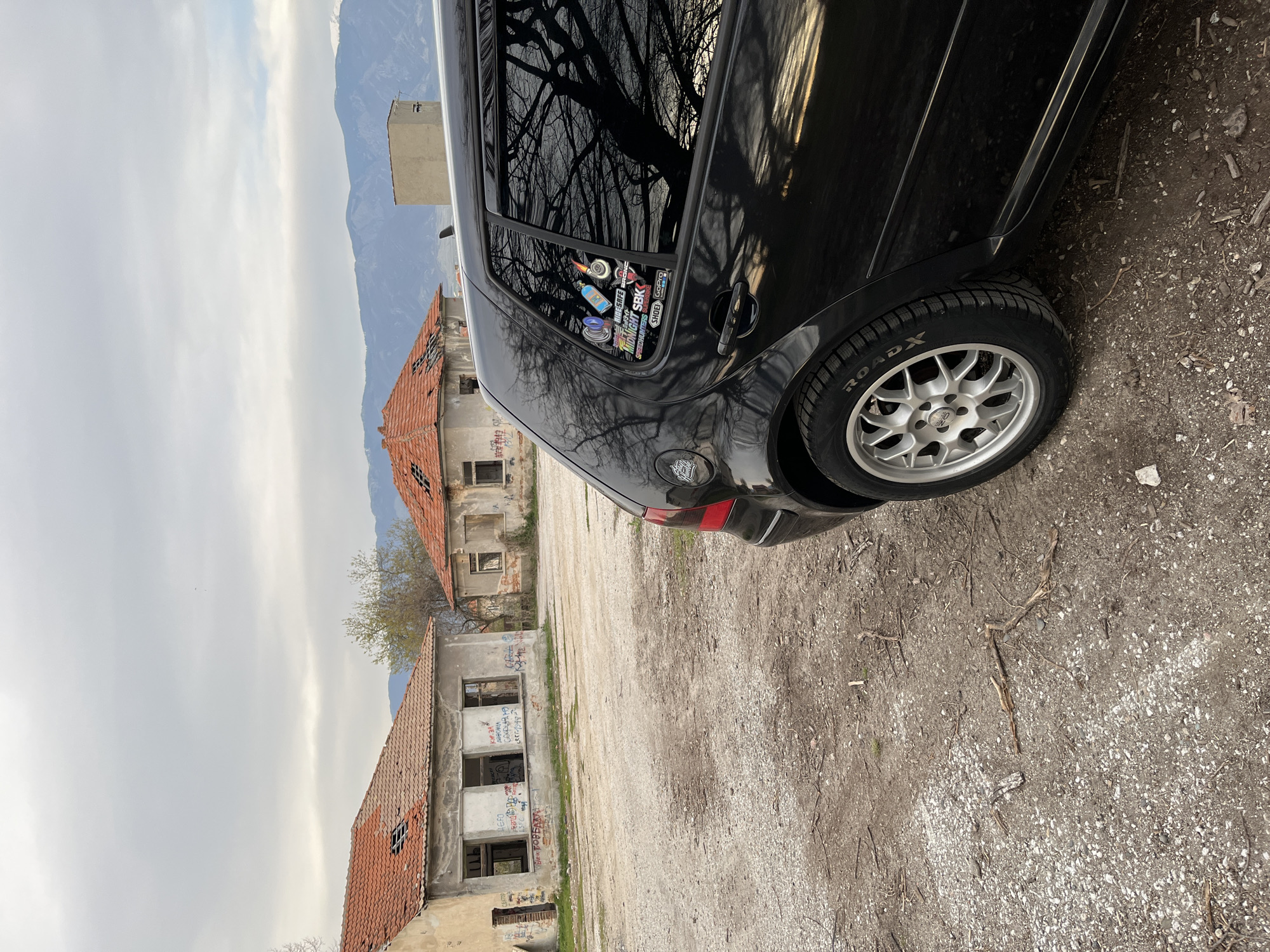 Black car parked near dilapidated buildings in Karavelovo, Bulgaria