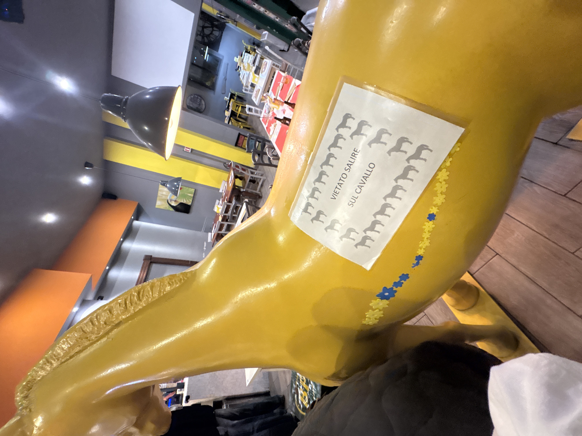Women pose with yellow horse sculpture in Milan cafe