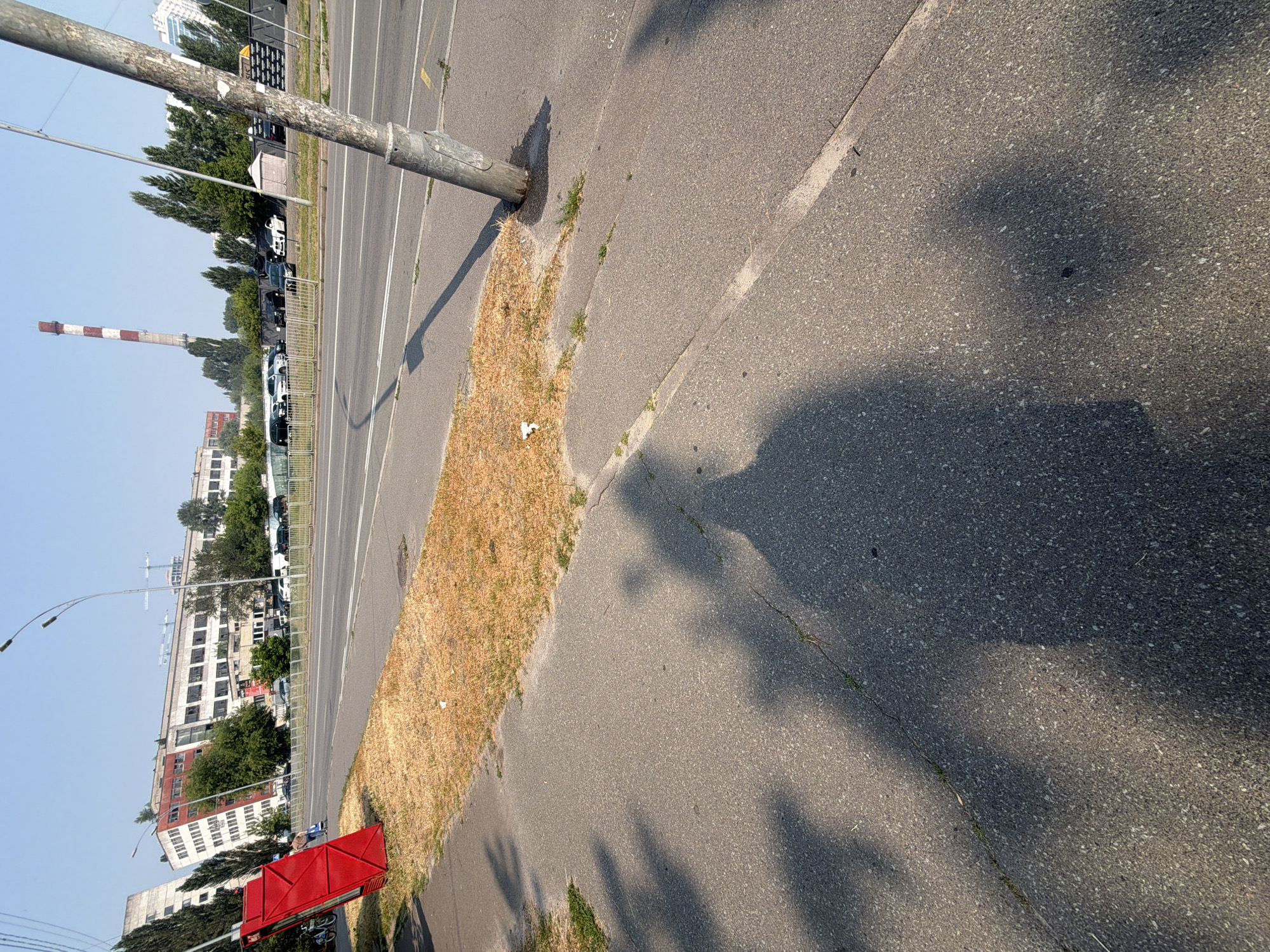 Summer morning on a Kyiv sidewalk near a red kiosk