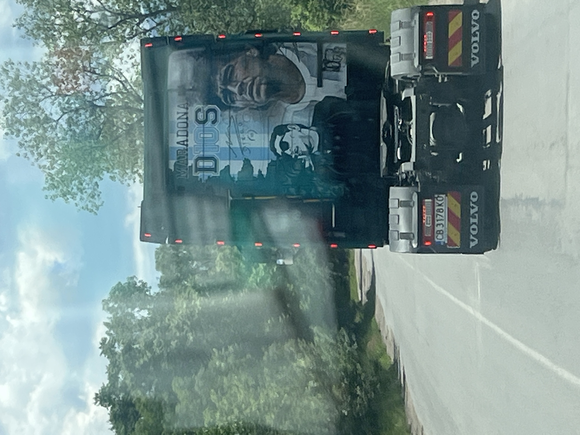 Truck displays Diego Maradona mural while driving on road