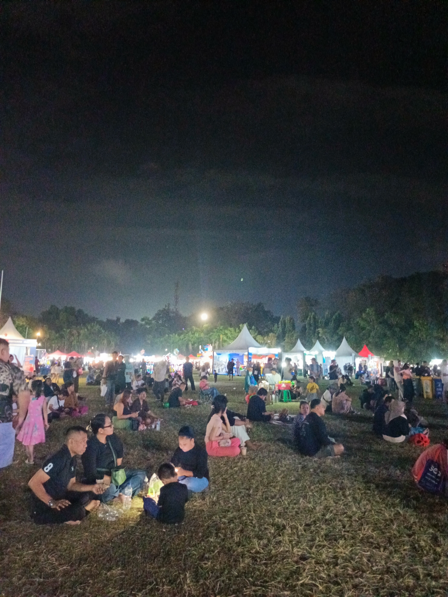 Nighttime gathering on a grassy field in Denpasar