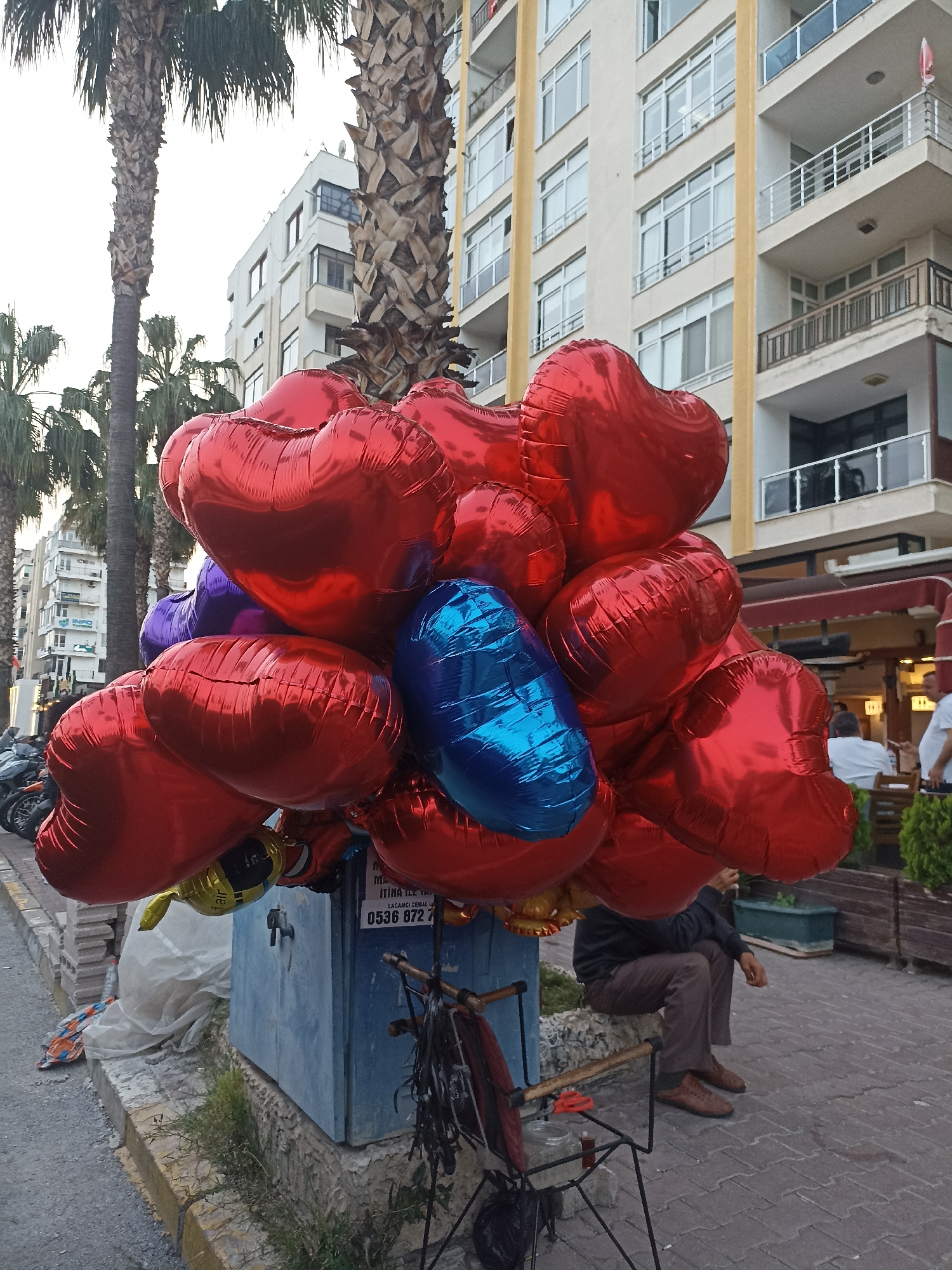 Colorful heart balloons spotted on Yenişehir sidewalk during sunset