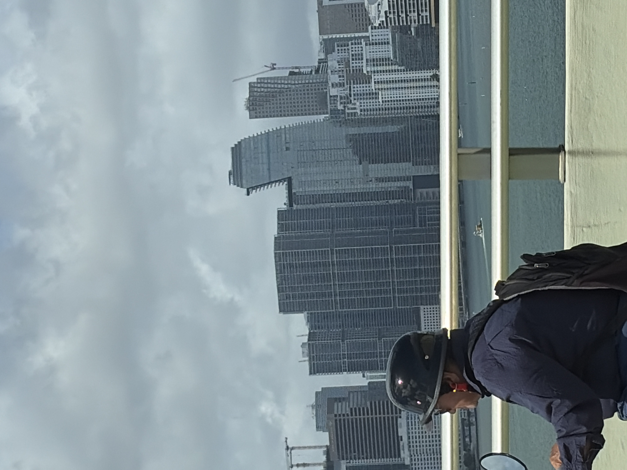Person in motorcycle gear views Miami skyline from bridge