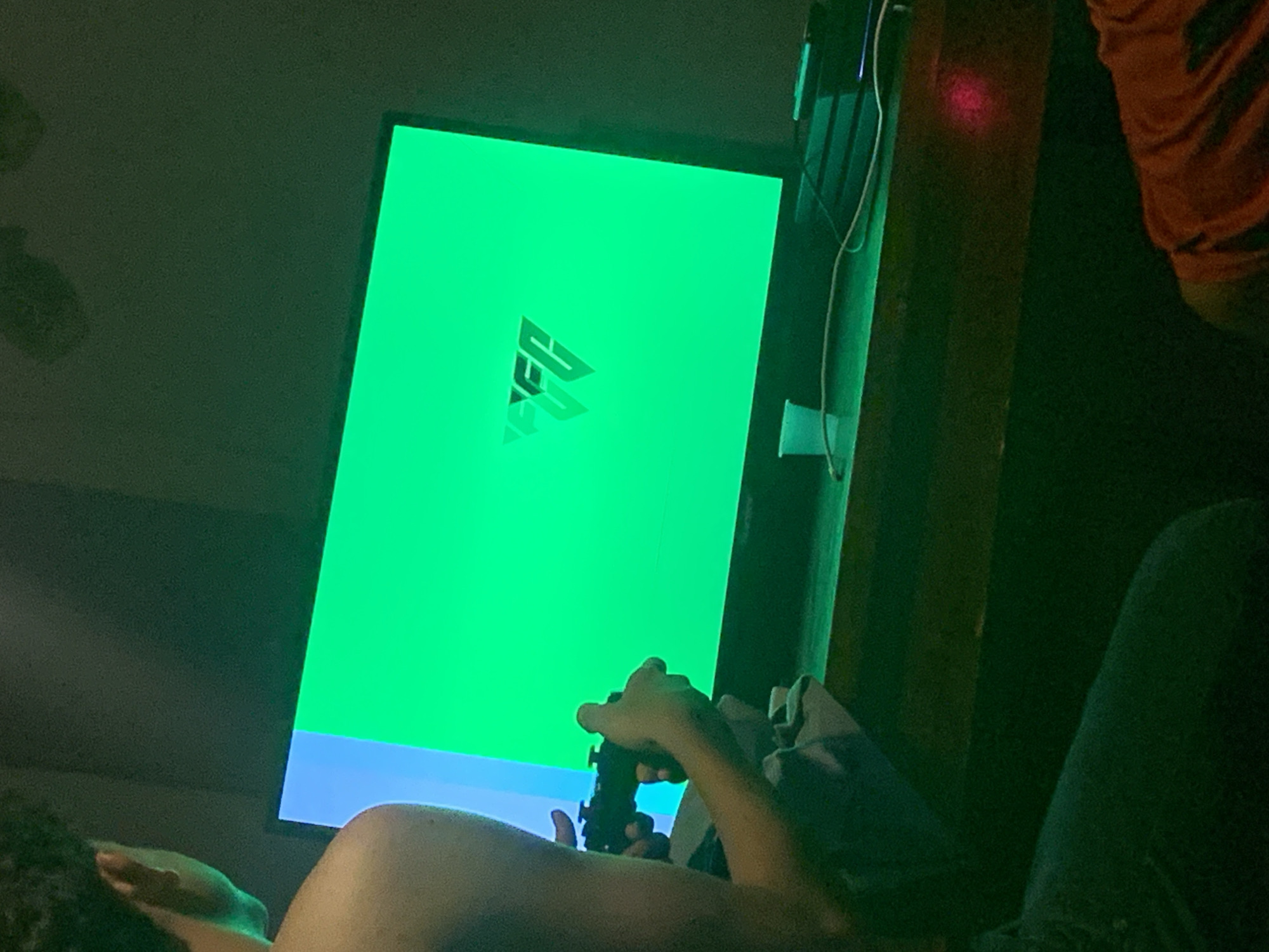 Person gaming with controller, green logo screen visible