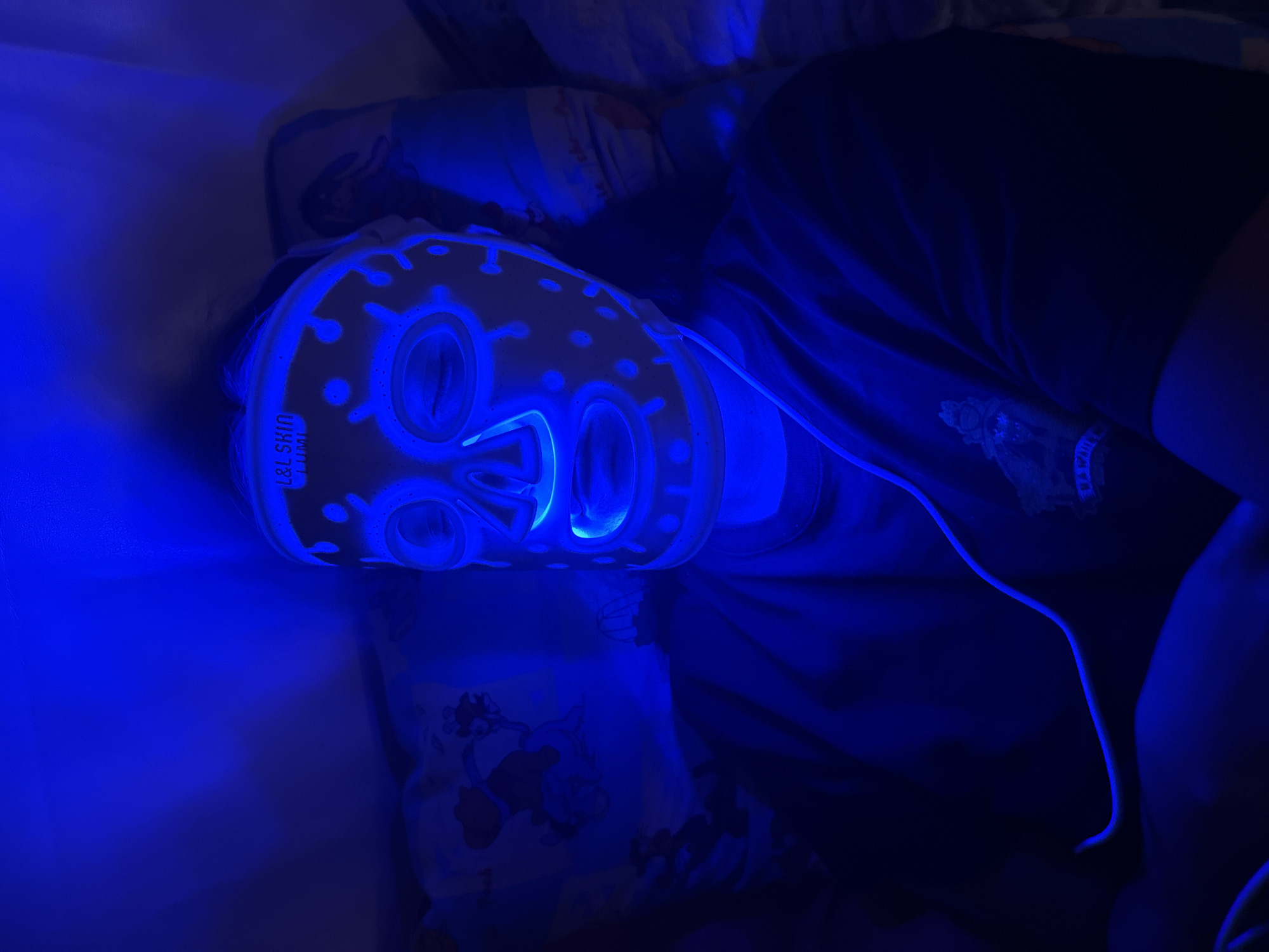 Person uses LED light therapy mask in Russian home