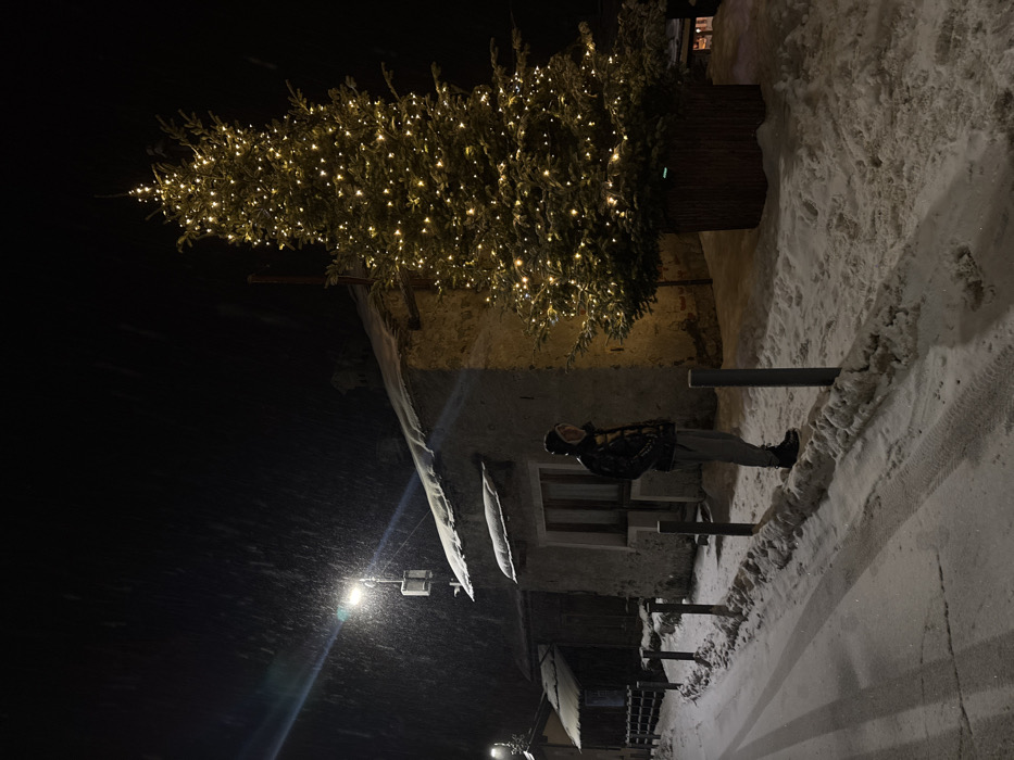 Person moves through snow-covered Italian valley amid Christmas decorations