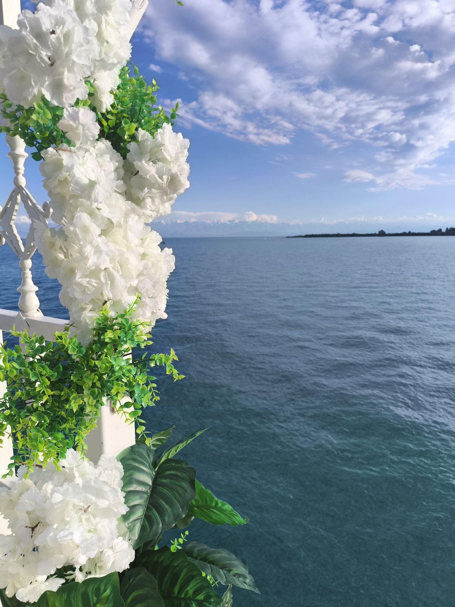 Issyk-Kul Lake framed by flowers and a white railing