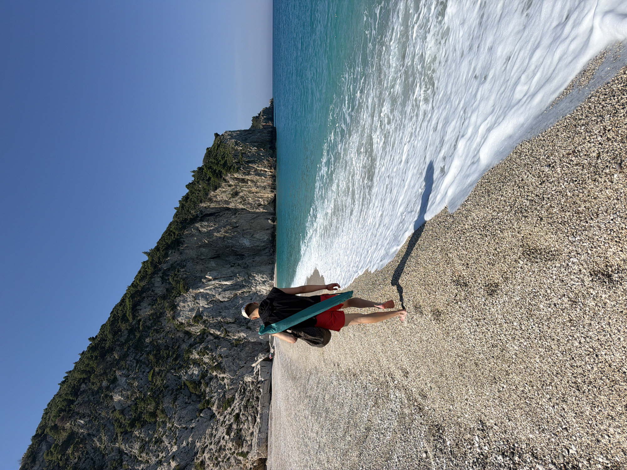 Man walks barefoot on Lefkada beach near limestone cliffs
