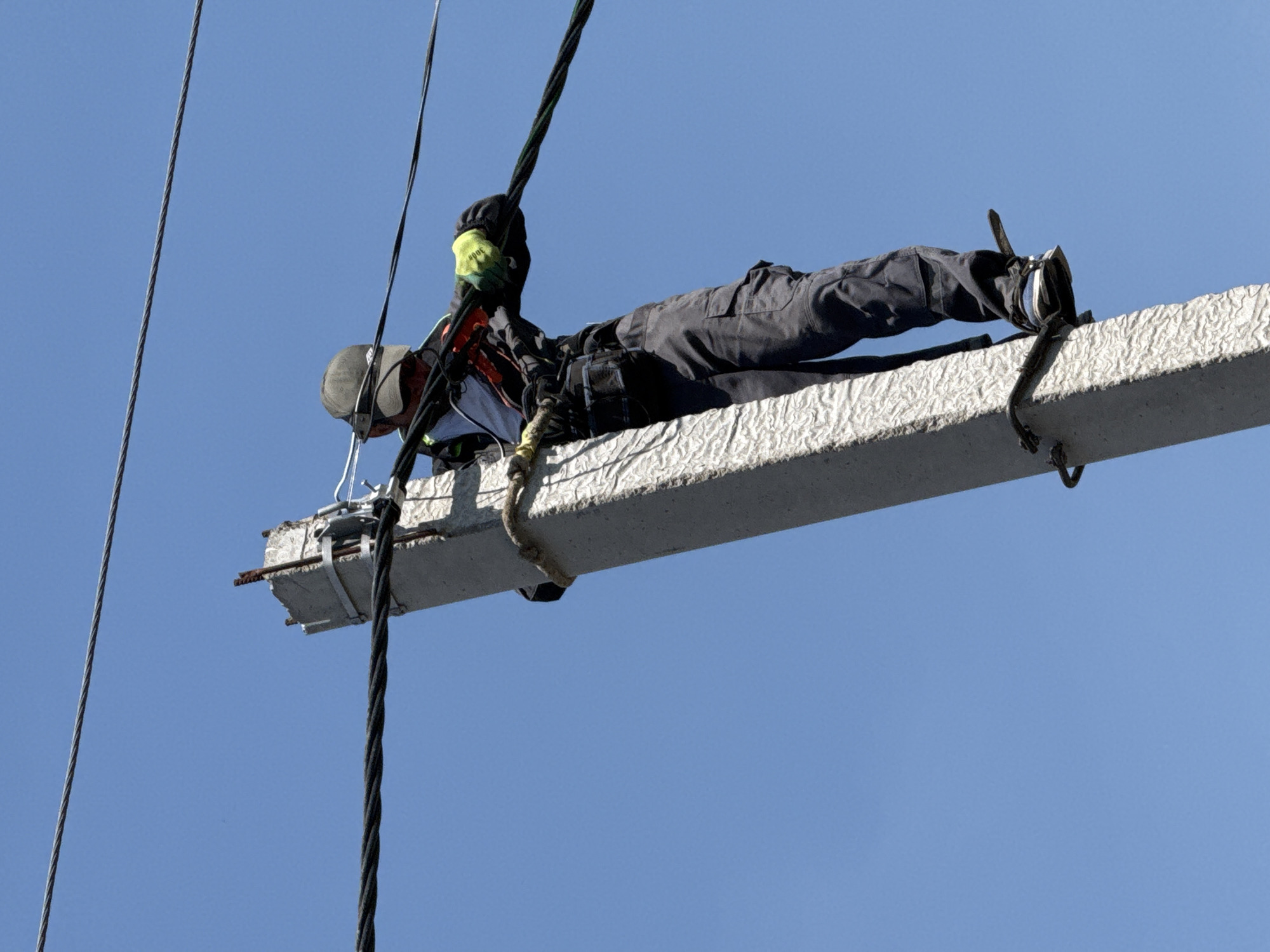 Construction worker performs high-altitude beam work with safety equipment
