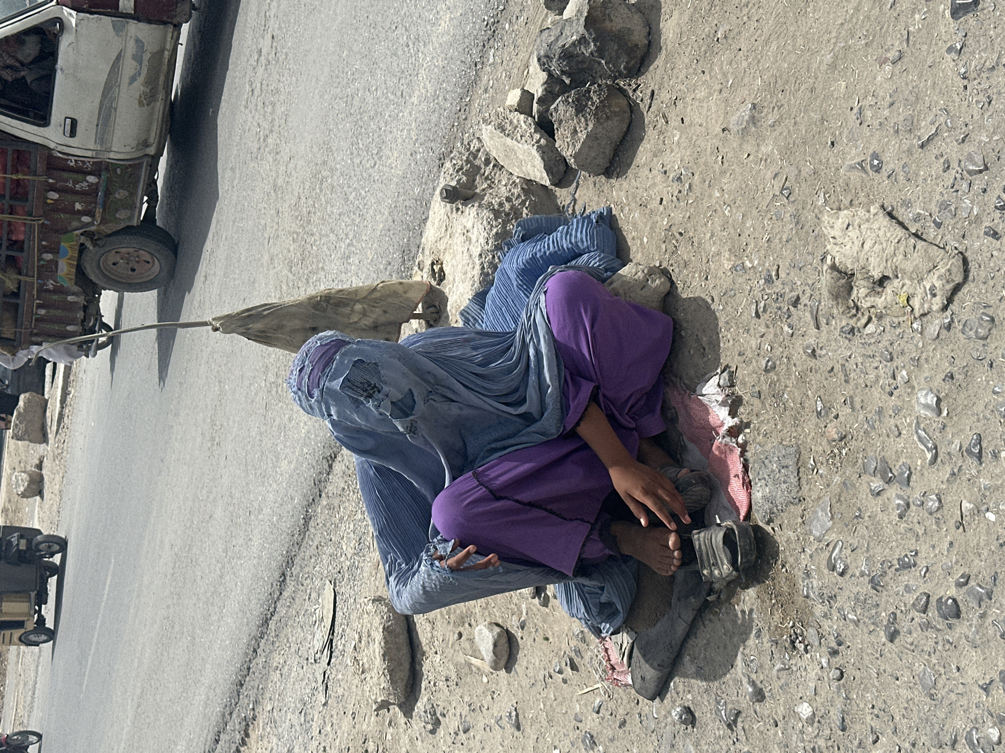 Person in burqa sits roadside in Quetta, Pakistan