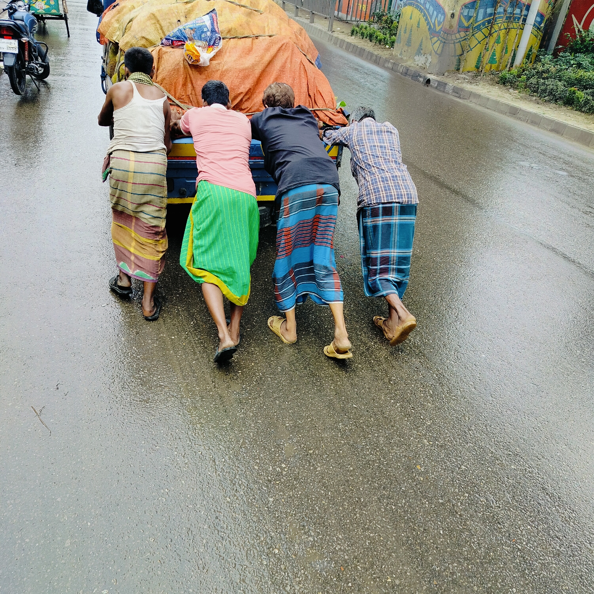 Wet-street hauling and morning prayers in Dhaka