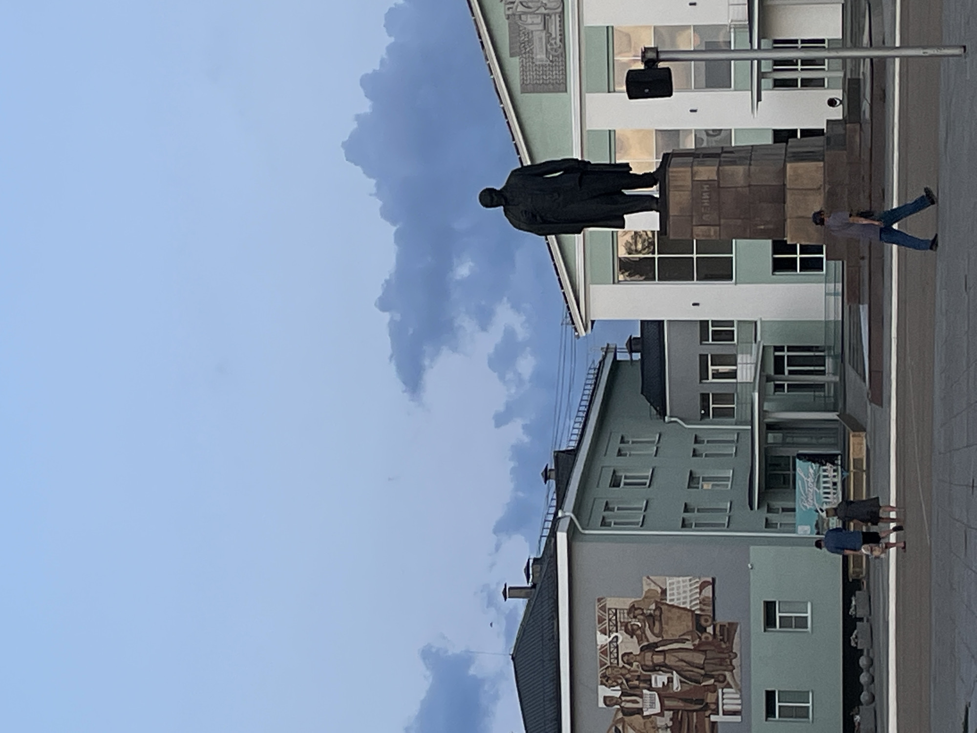 Lenin statue in a public square under a changing sky