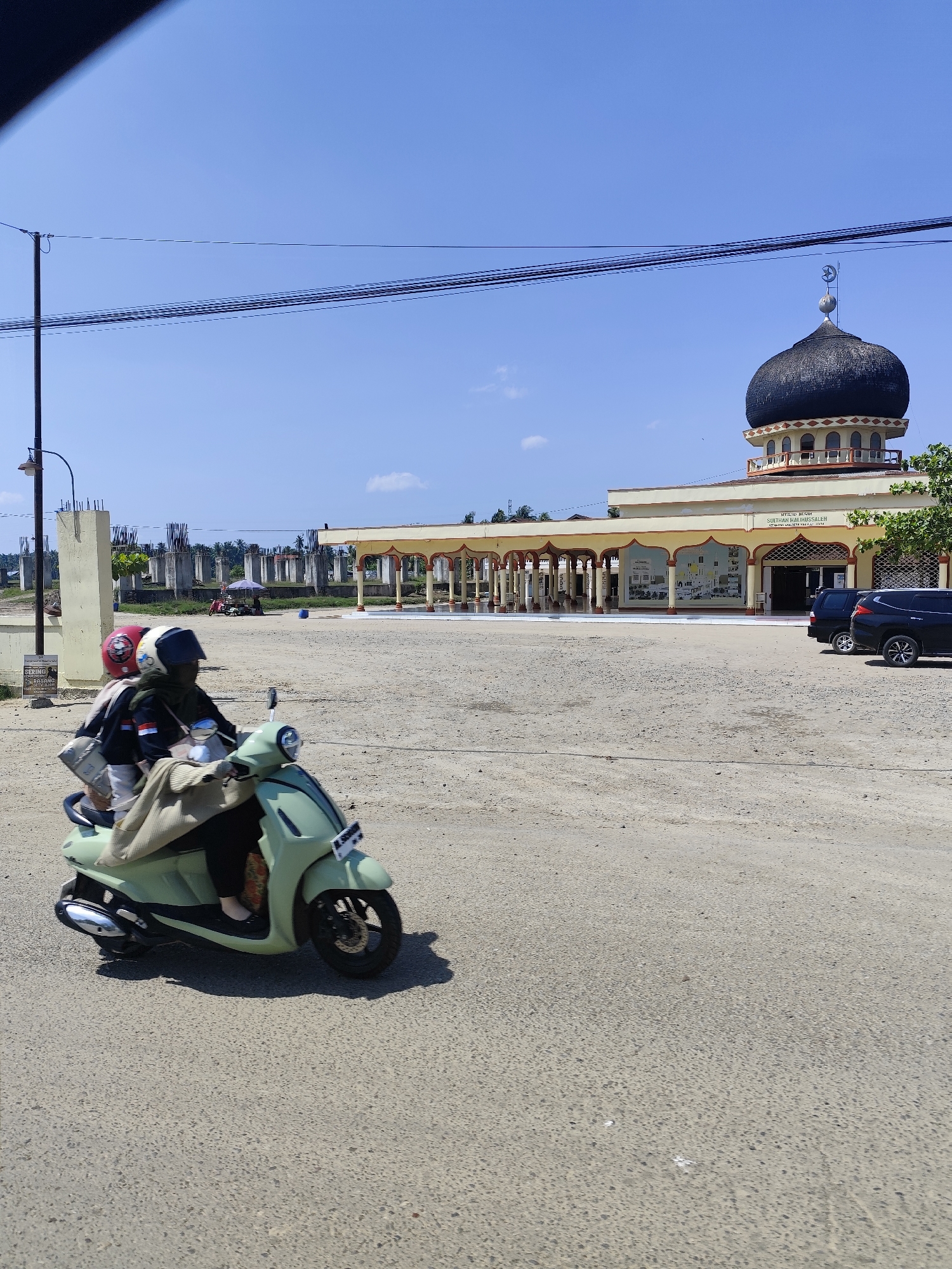 Two riders on scooter outside Indonesian mosque