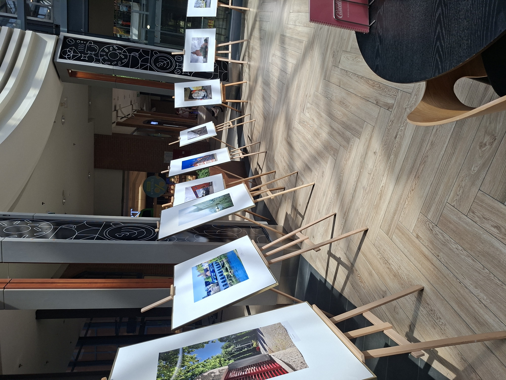 Browsing a mall photo exhibition with escalators and atrium in view