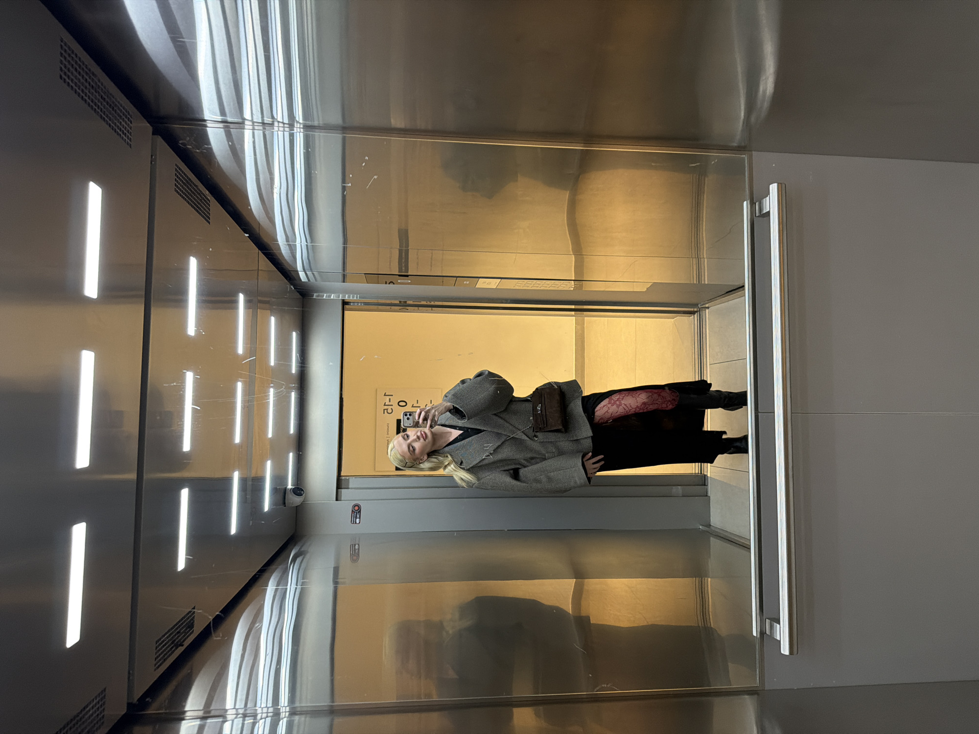 Woman takes selfie in Belgrade elevator, captured in purple-lit setting
