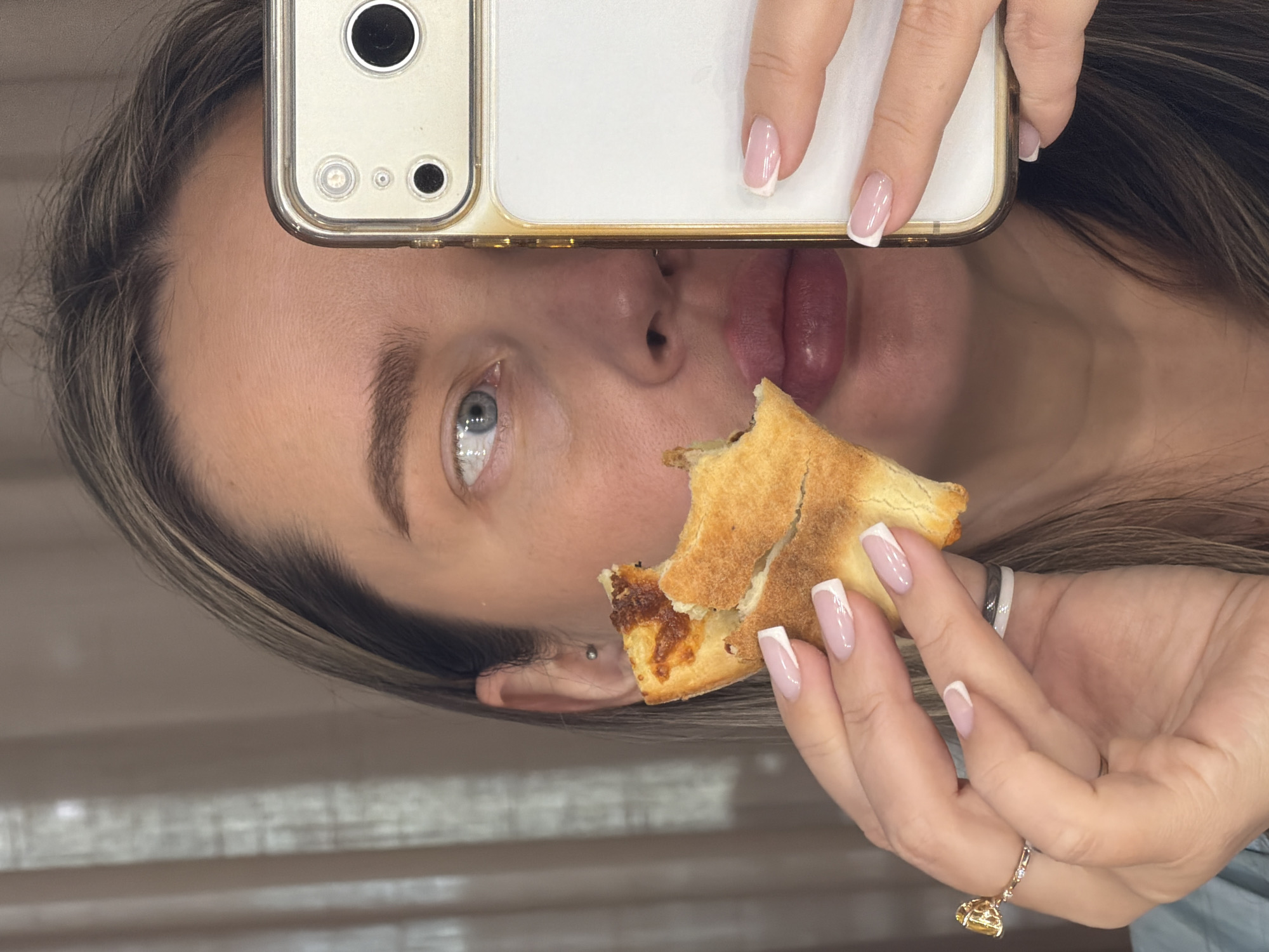 Woman eating pizza while using phone in Moscow