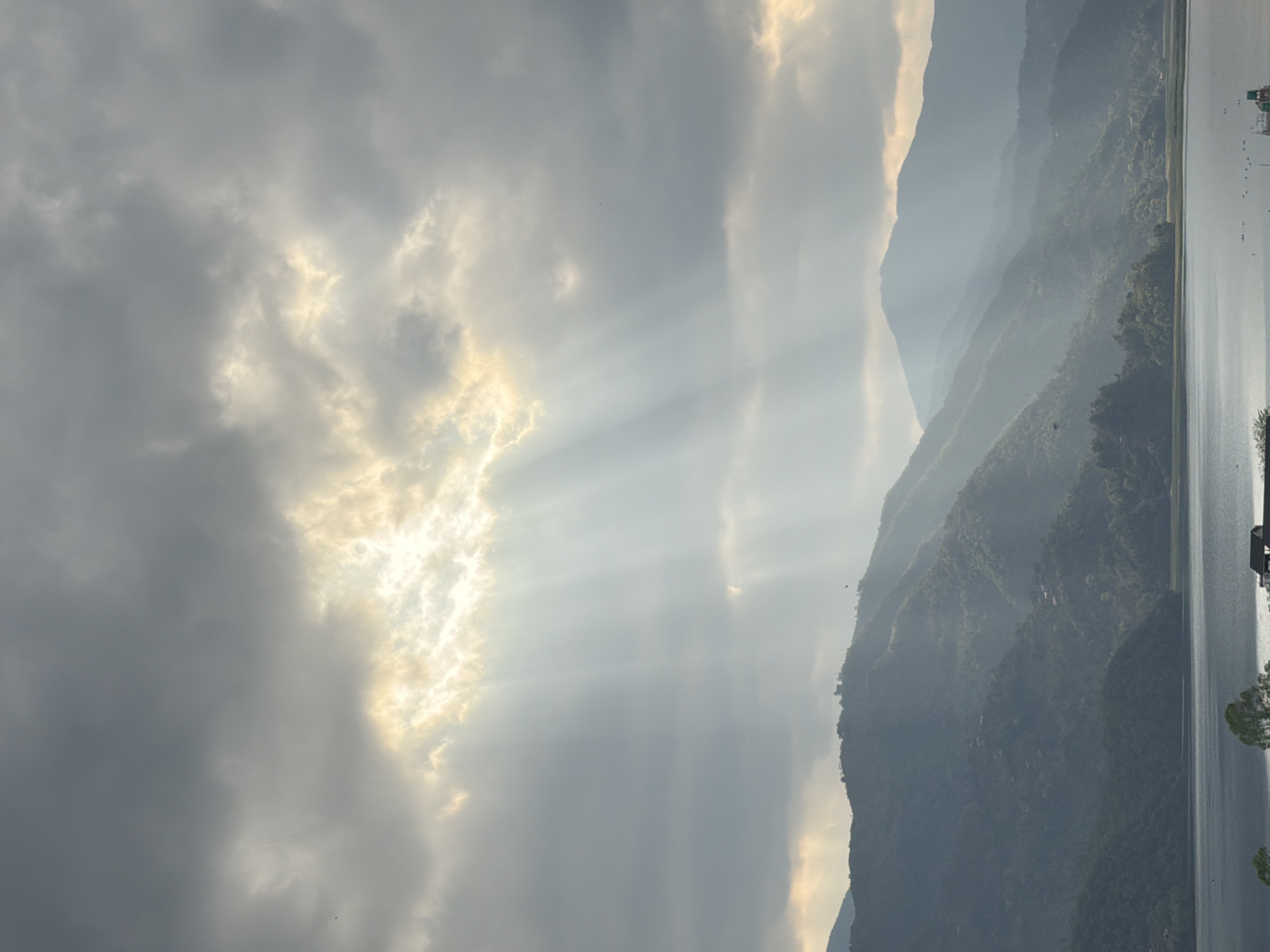 Sunbeams pierce clouds over Pokhara's mountain landscape