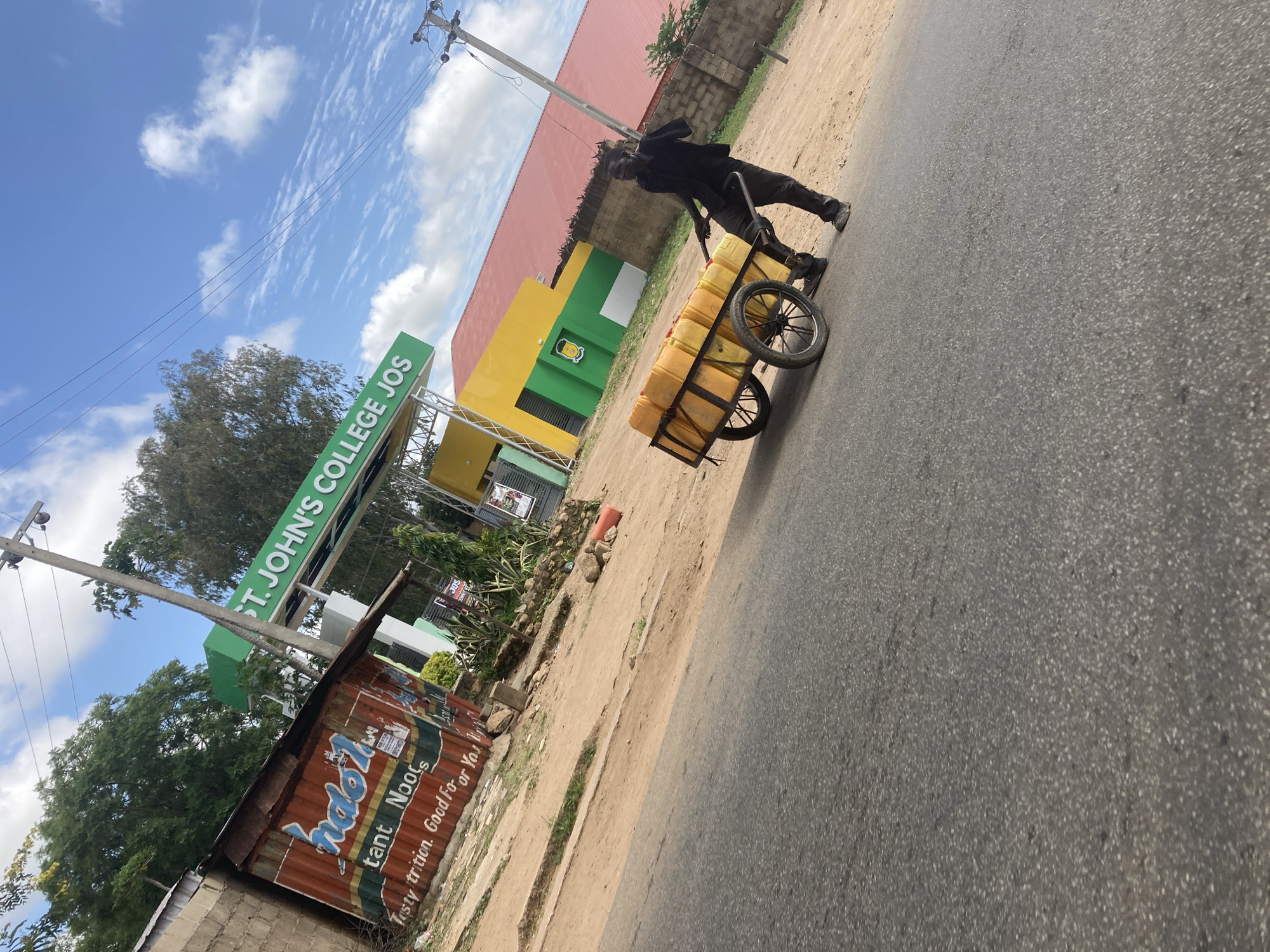 Street traffic and water delivery on a Jos, Nigeria road