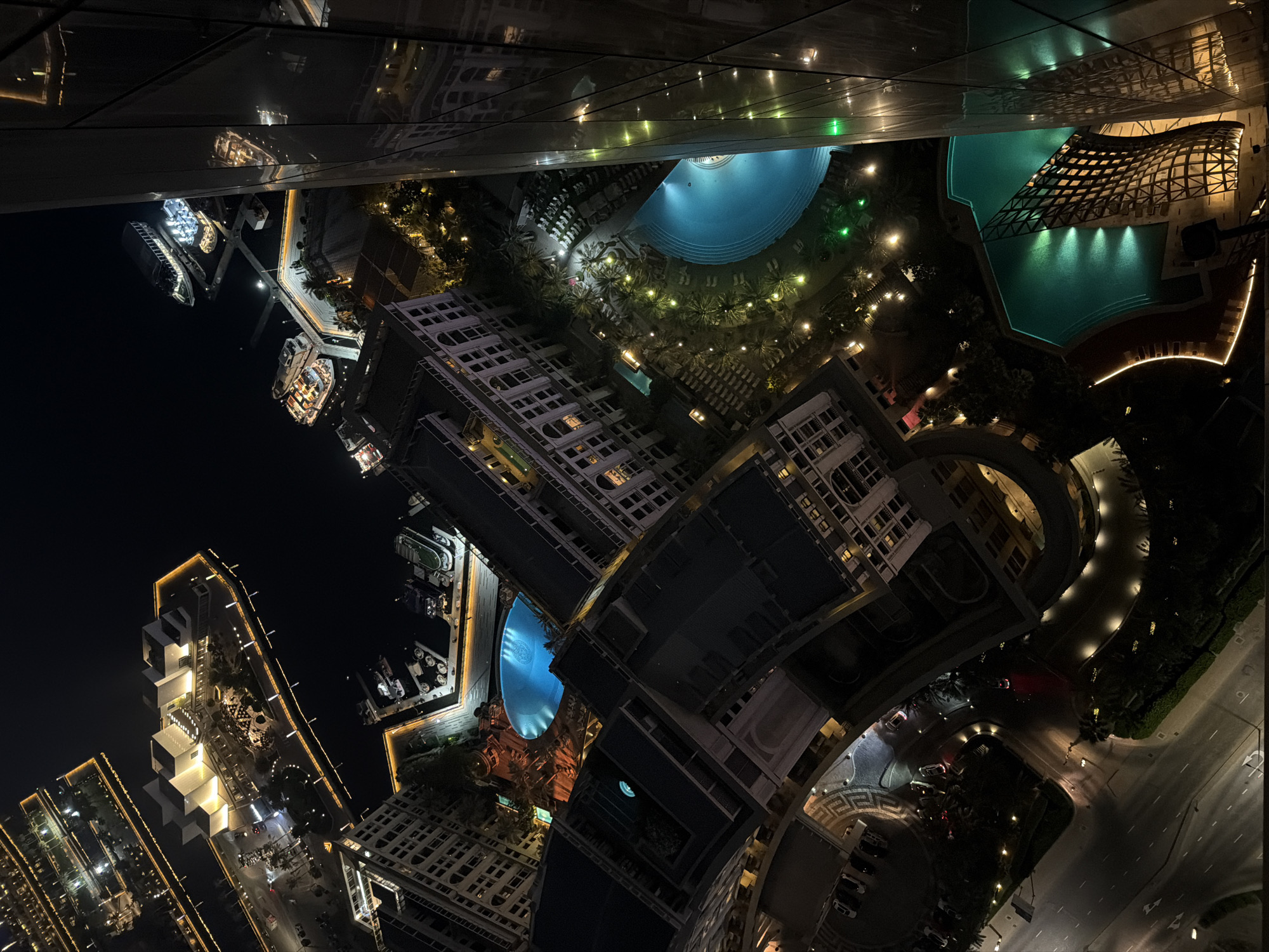 Dubai at night from above — skyline, waterways, and highways.