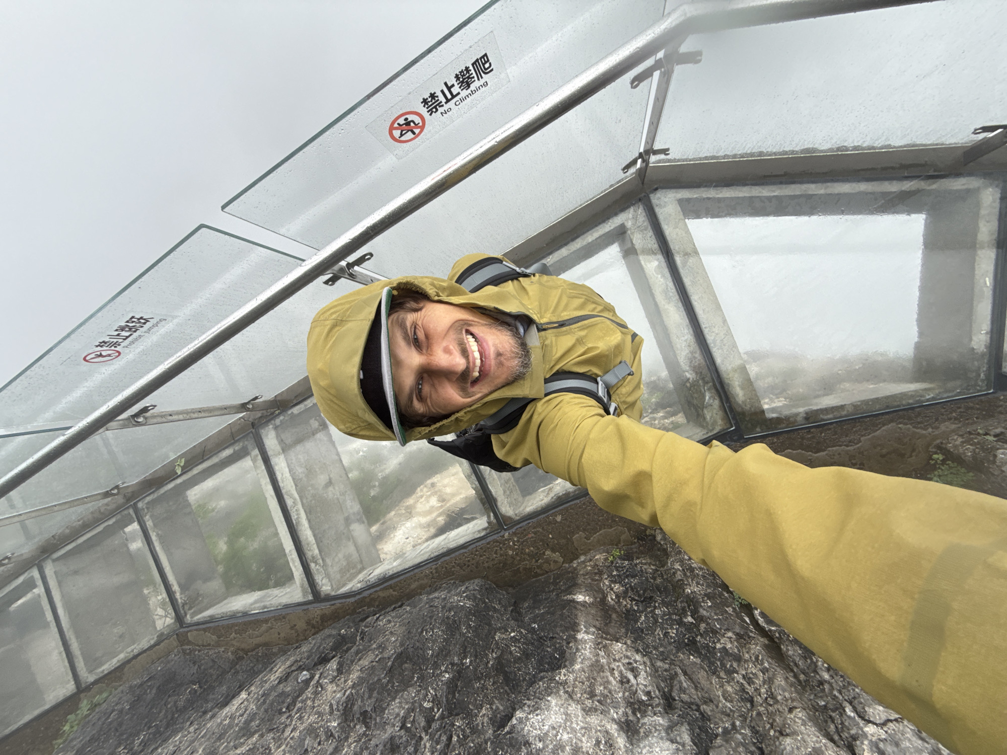 Tourist documents foggy morning visit to glass walkway in China