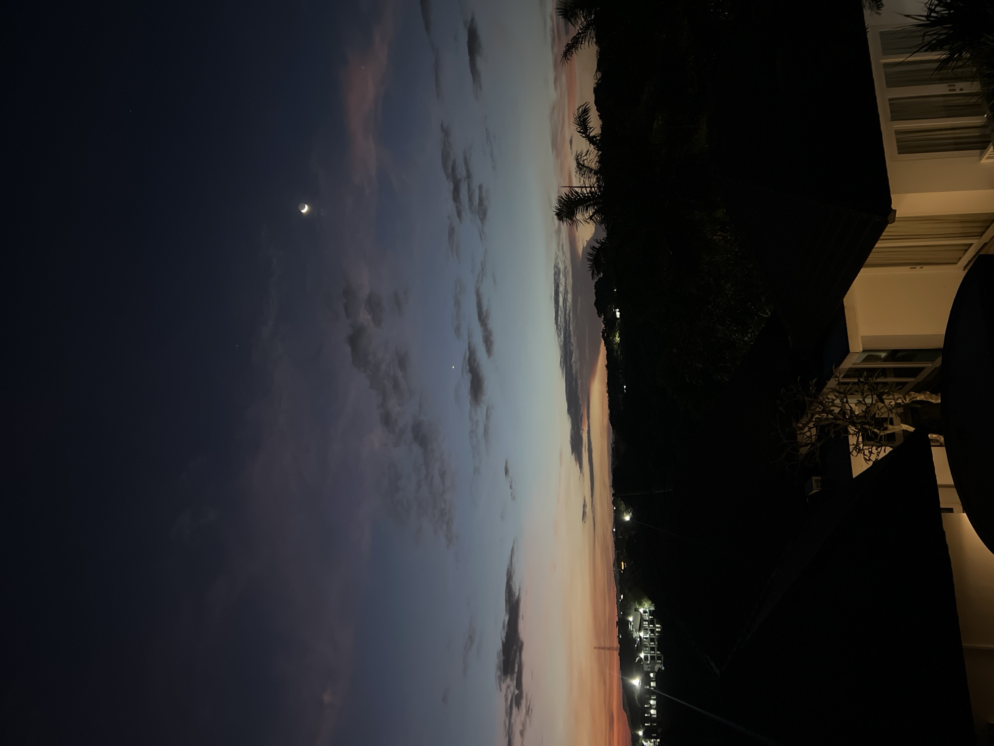 Crescent moon twilight scene witnessed from urban balcony