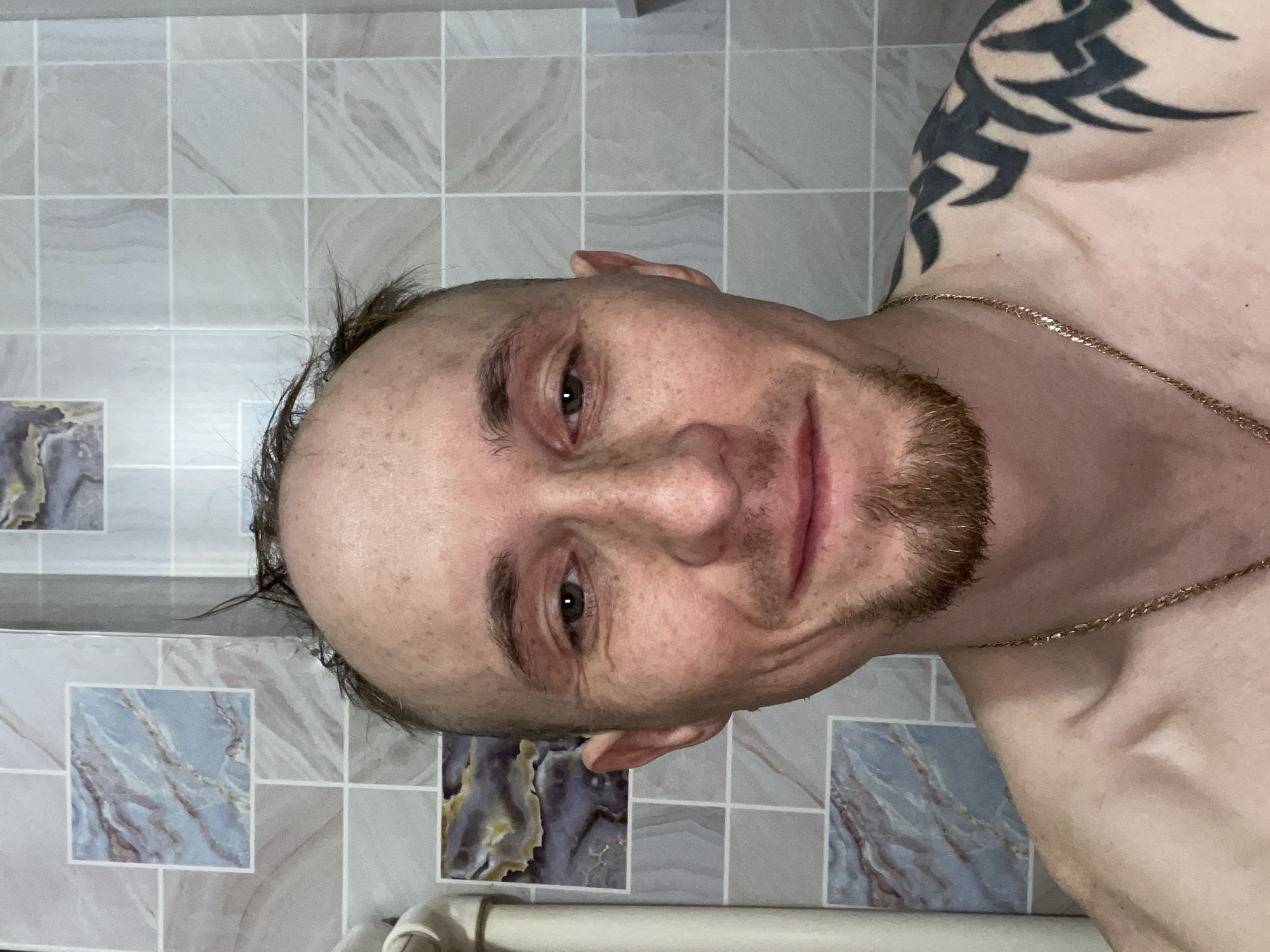 Man photographed shirtless against tiled wall in Devyatovo