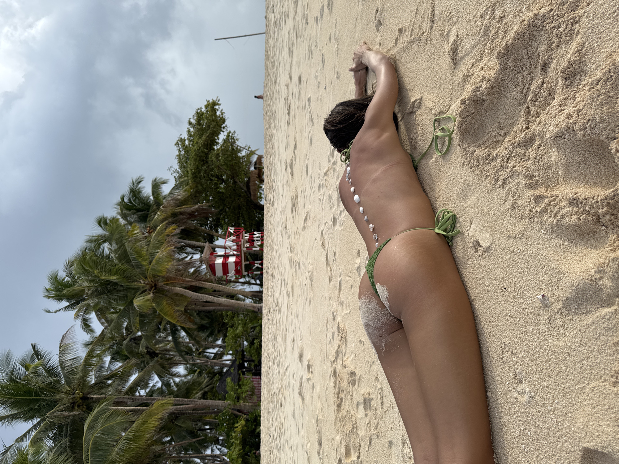 Beach visitor arranges decorative shells on sunbather in Philippines