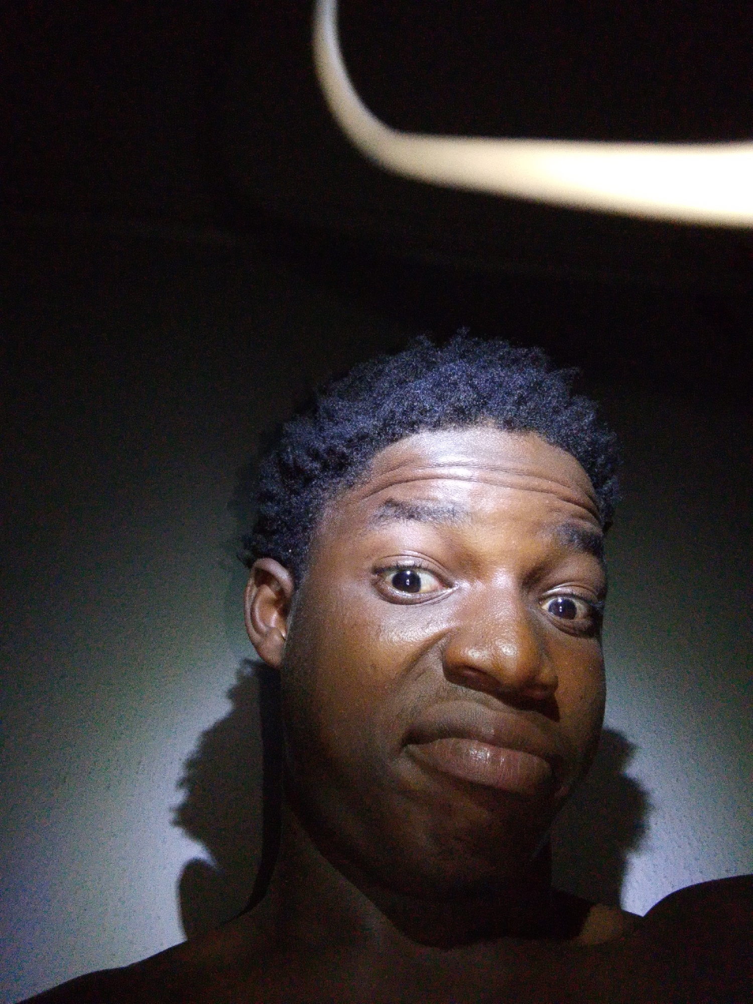 Person photographed making playful faces in dramatic lighting