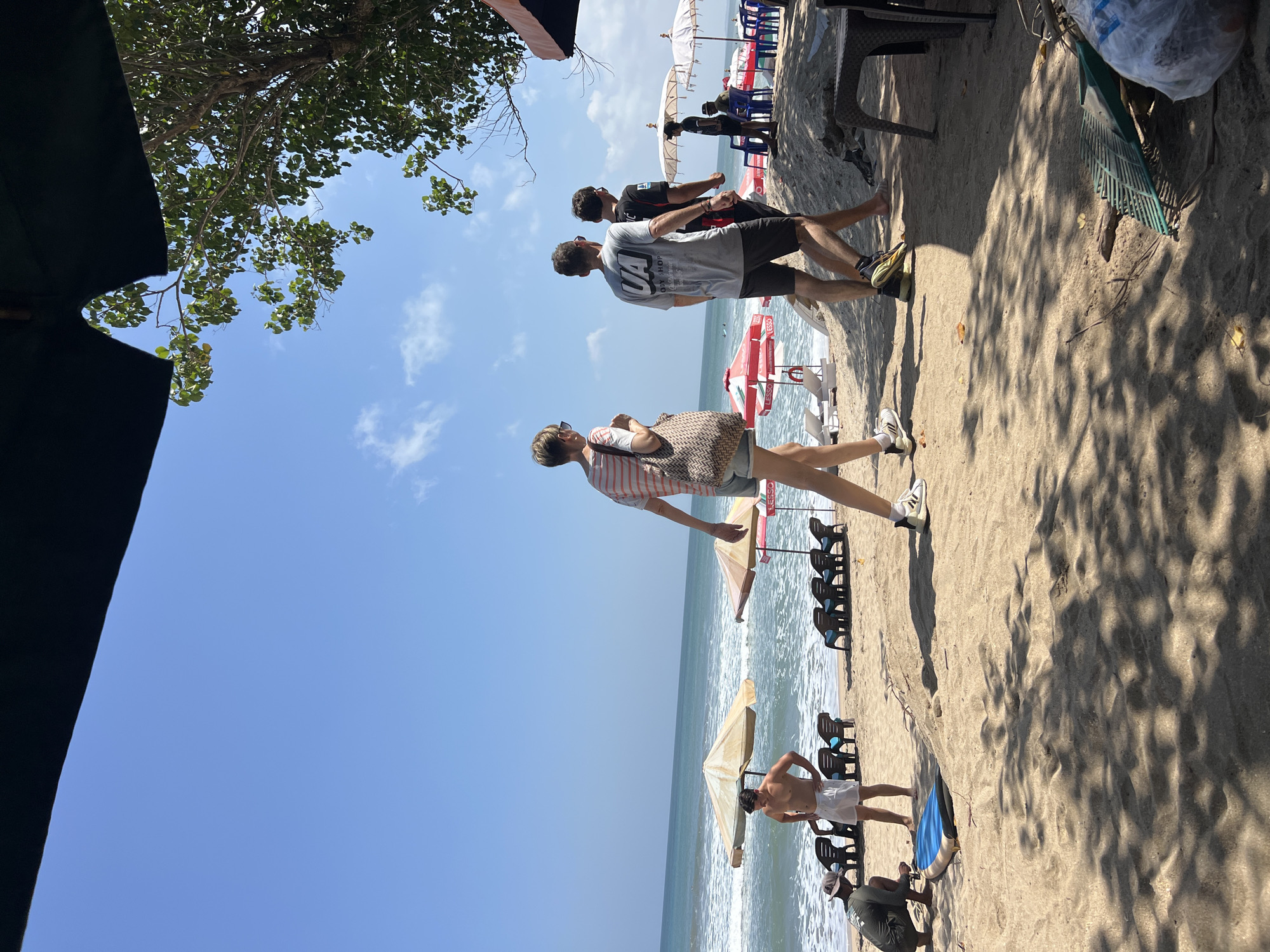 Surfers and beach crowds fill Kuta Beach on a sunny morning