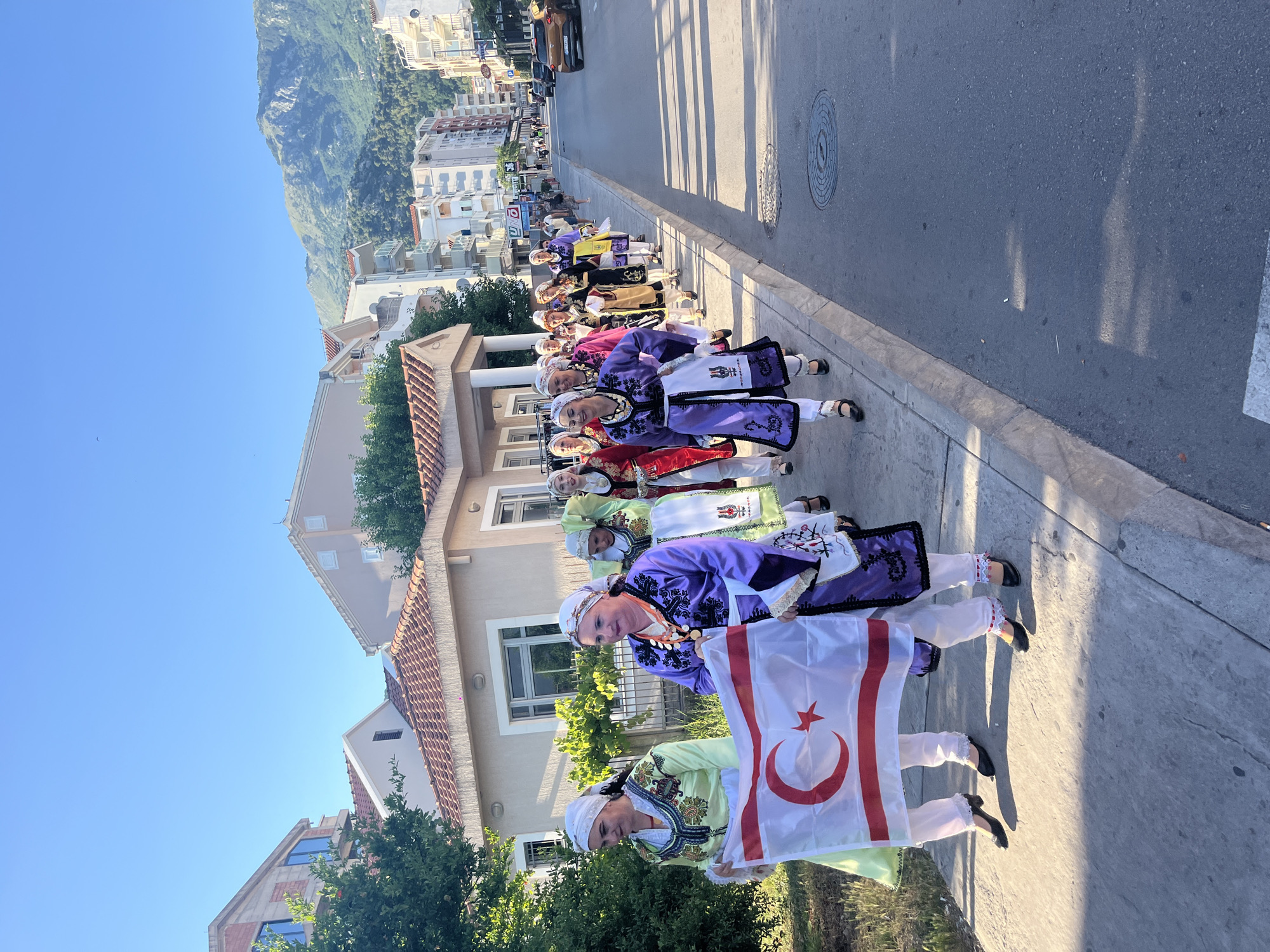 Afternoon street life in a mountain-backed city with traditional parade
