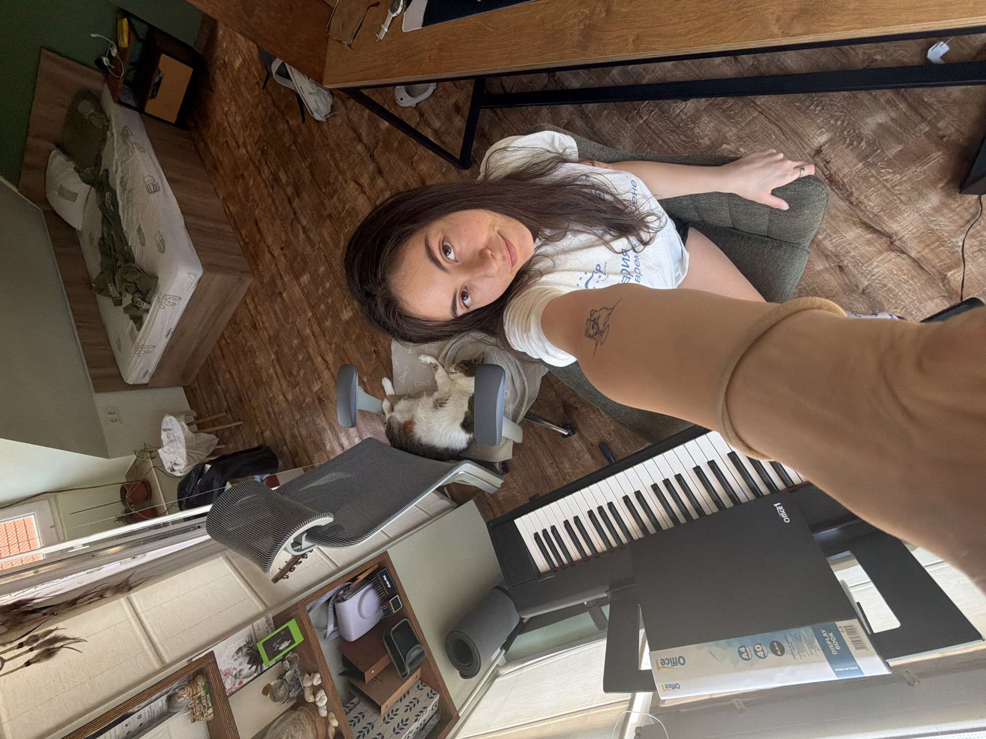 Woman takes selfie as cat naps nearby indoors