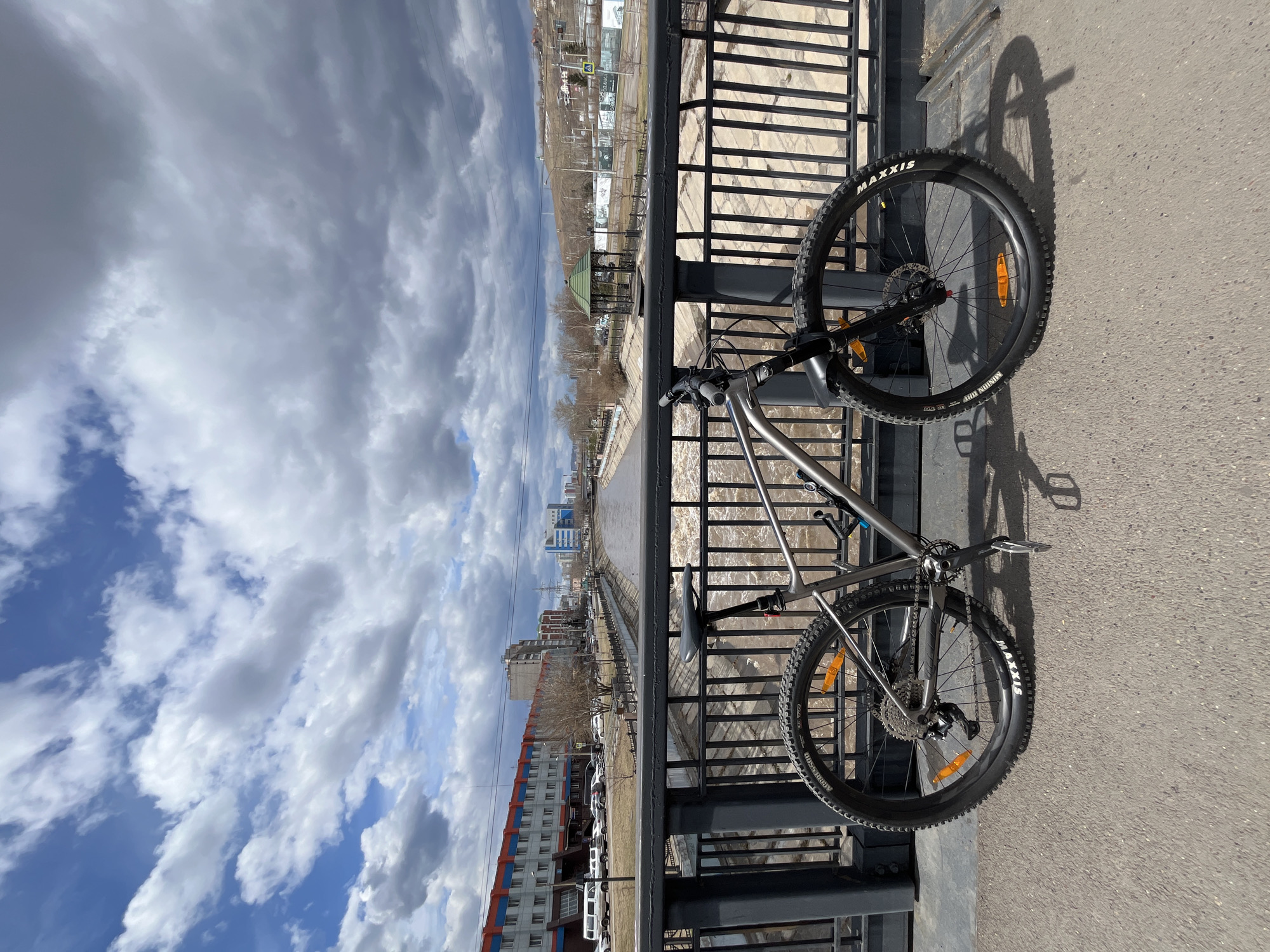 Early morning cyclist pauses on Krasnoyarsk bridge overlooking muddy river