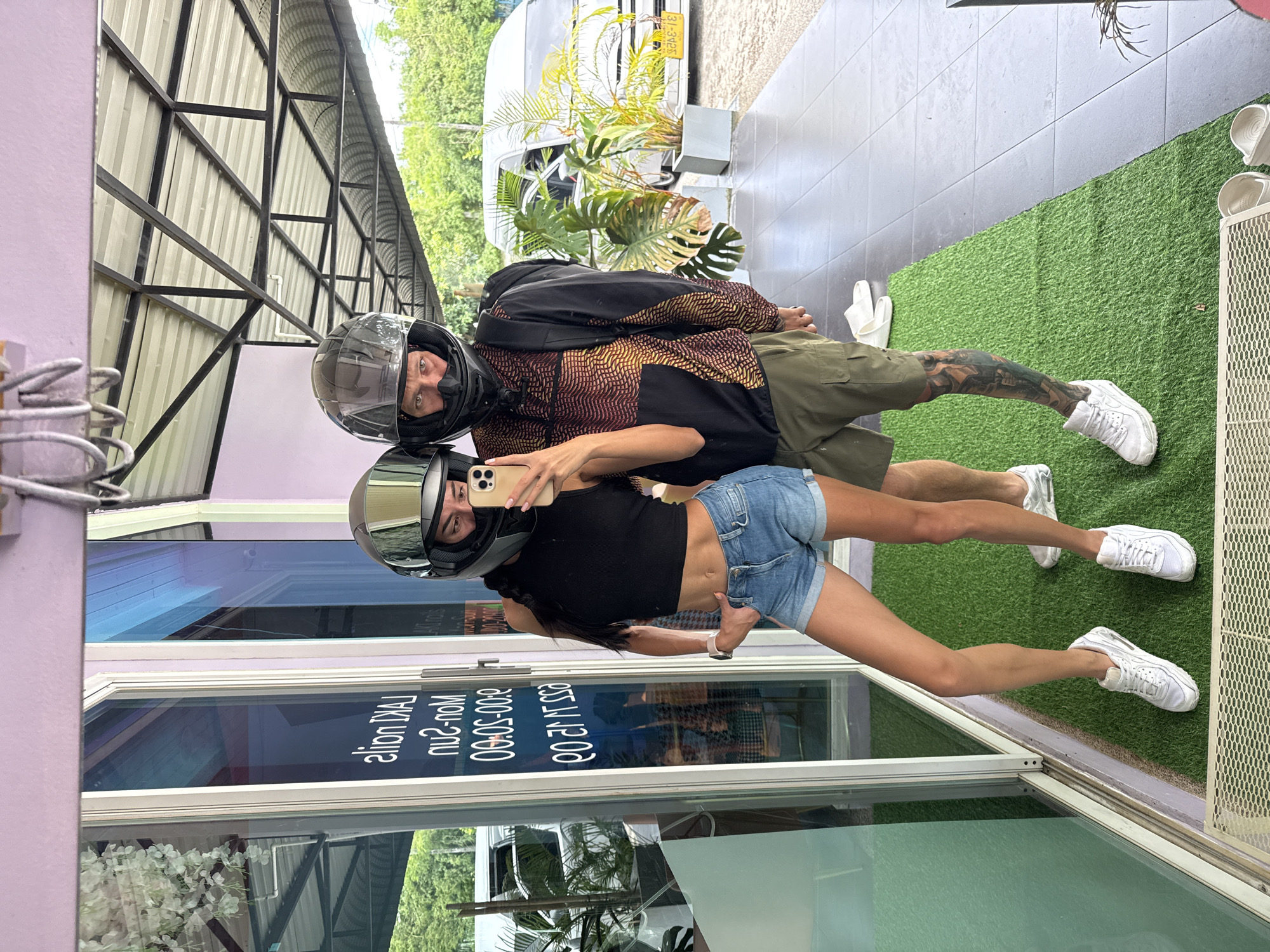Mirror selfie with helmets on outside Wichit storefront