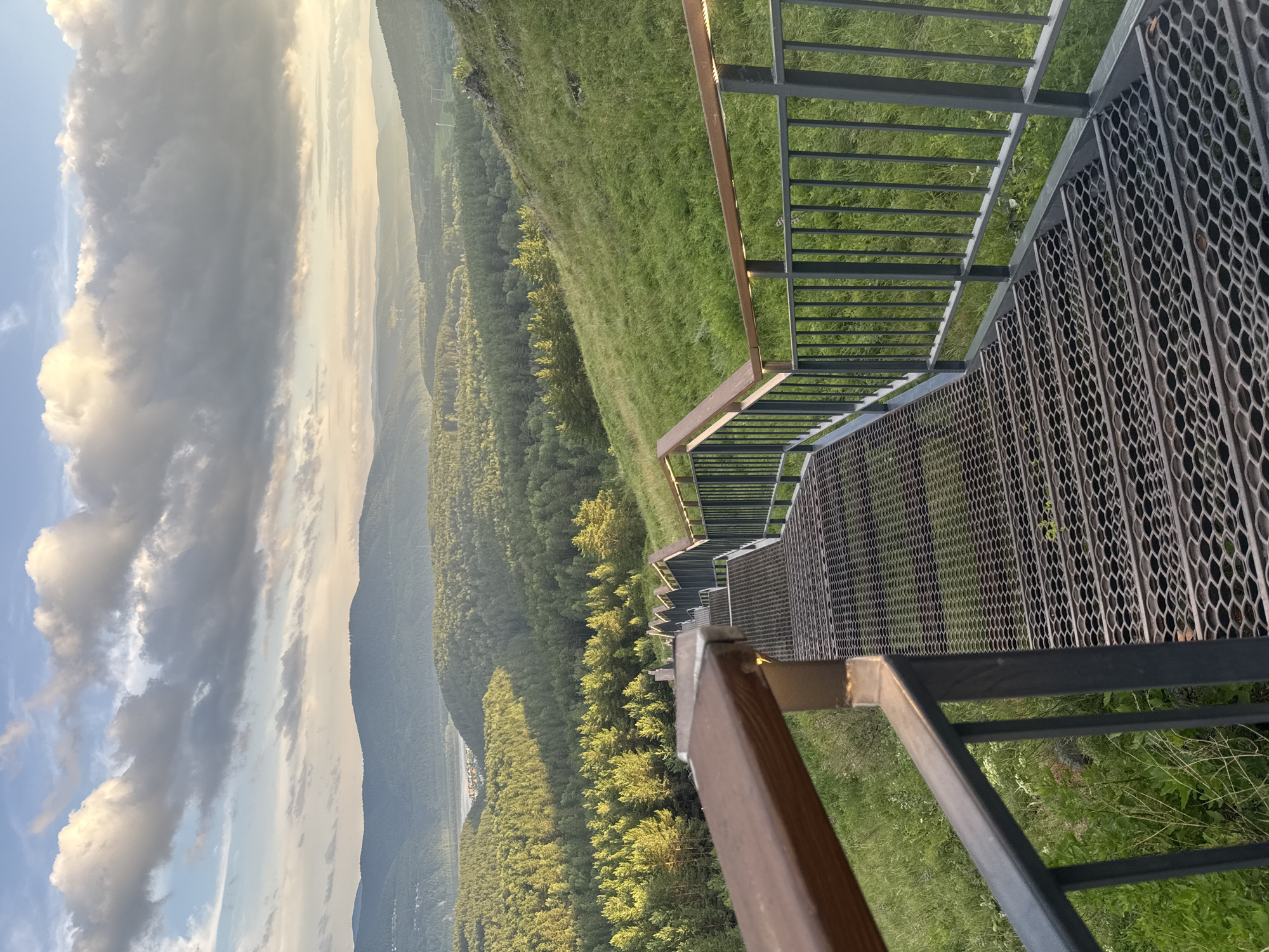 Metal staircase descends a hillside overlooking a wide Siberian valley.