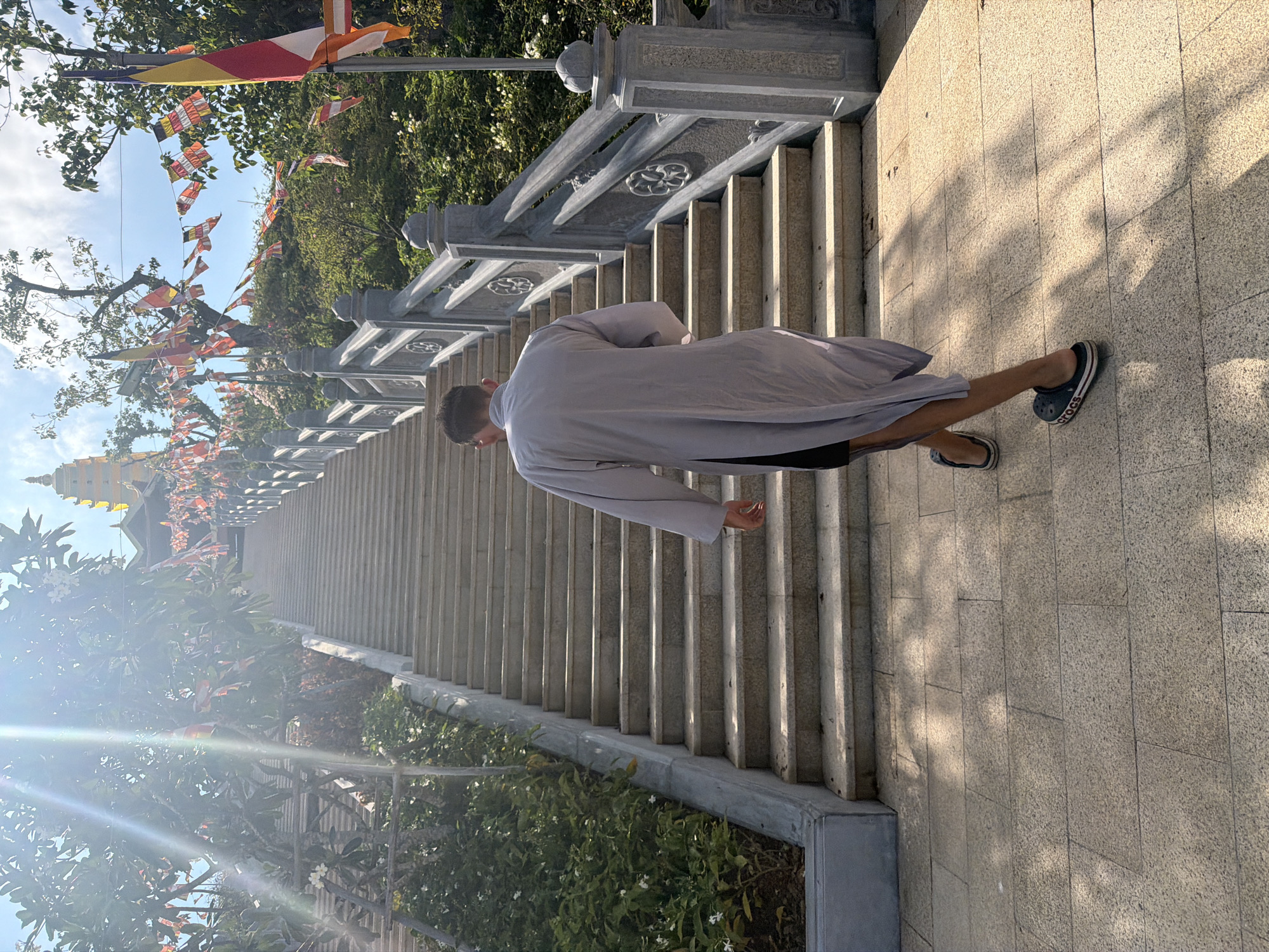Robed man descends pagoda stairs in Nha Trang temple complex