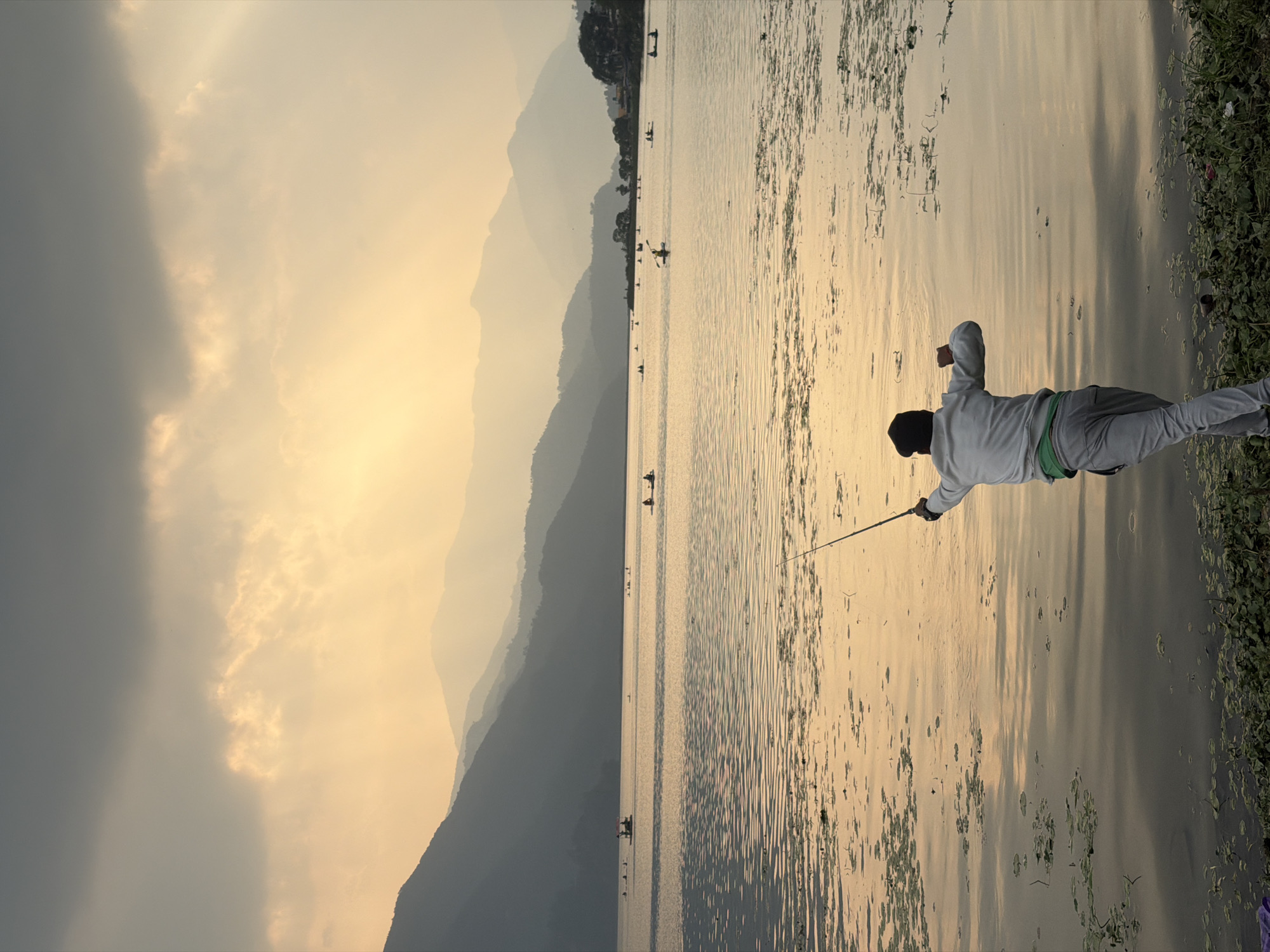 Angler fishes at Phewa Lake with Annapurna mountains backdrop