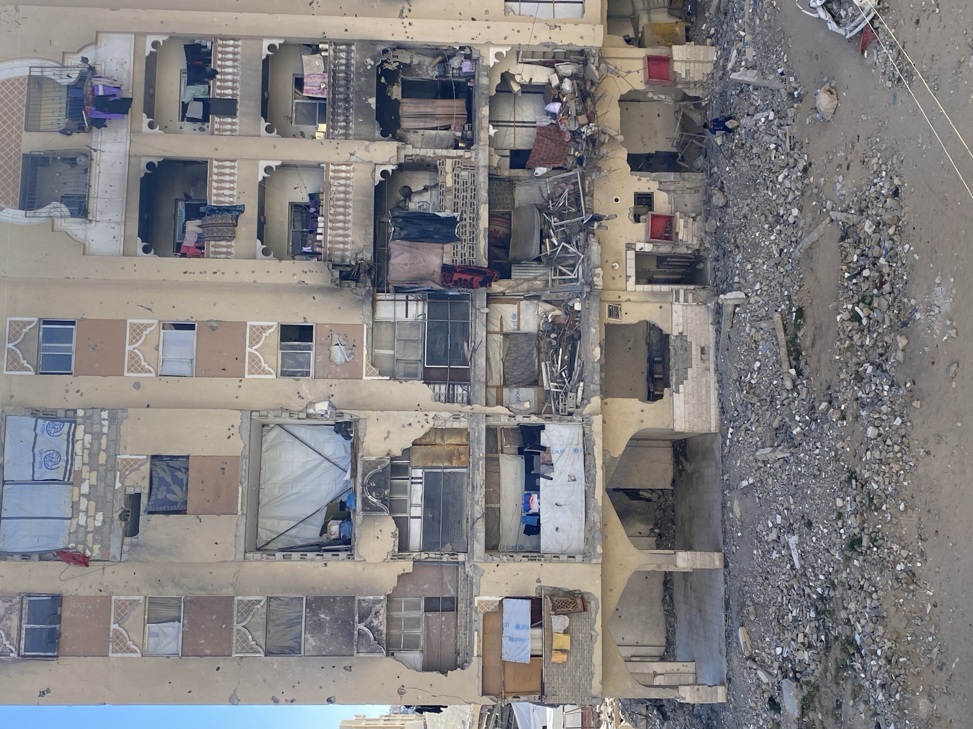 Damaged apartment building documented near debris-strewn street