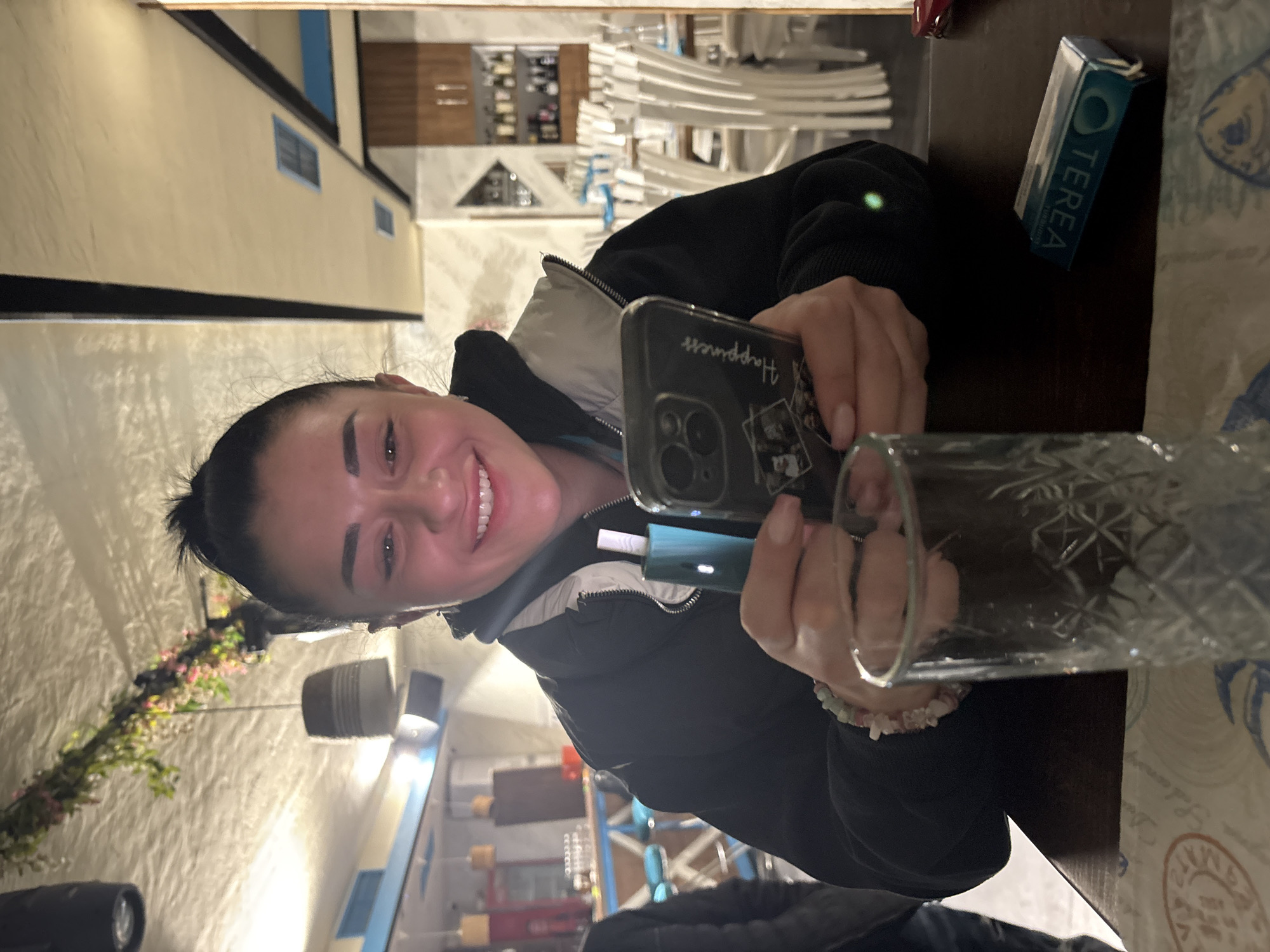 Woman photographed with phone and device in indoor setting