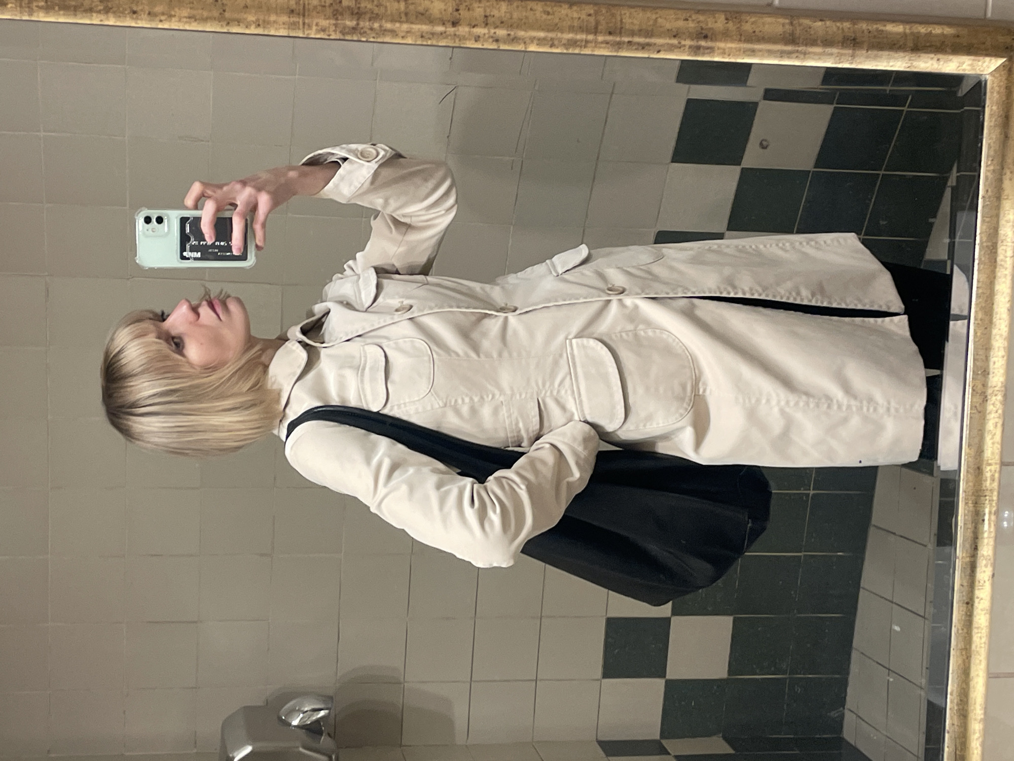 Person takes mirror selfie indoors, blonde hair visible