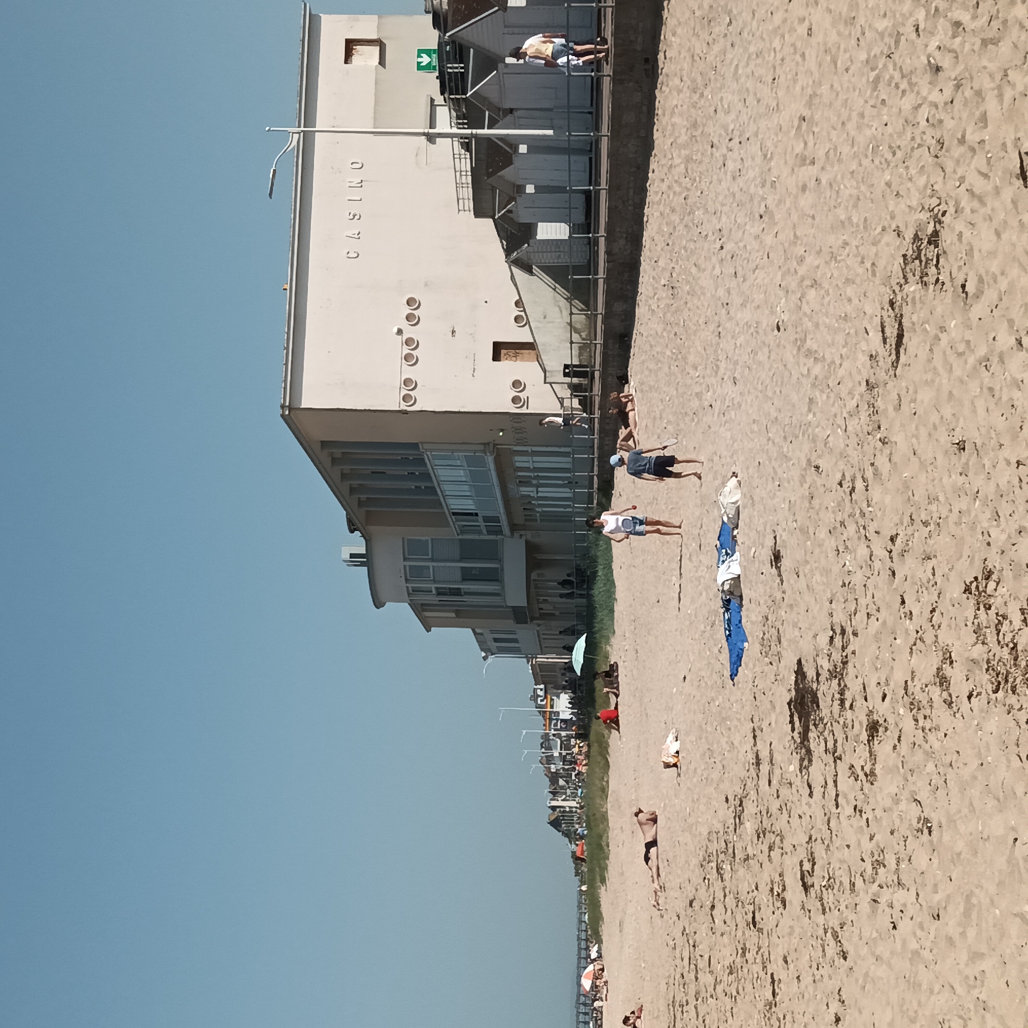 Beach day documented near casino with tennis, sailing activities