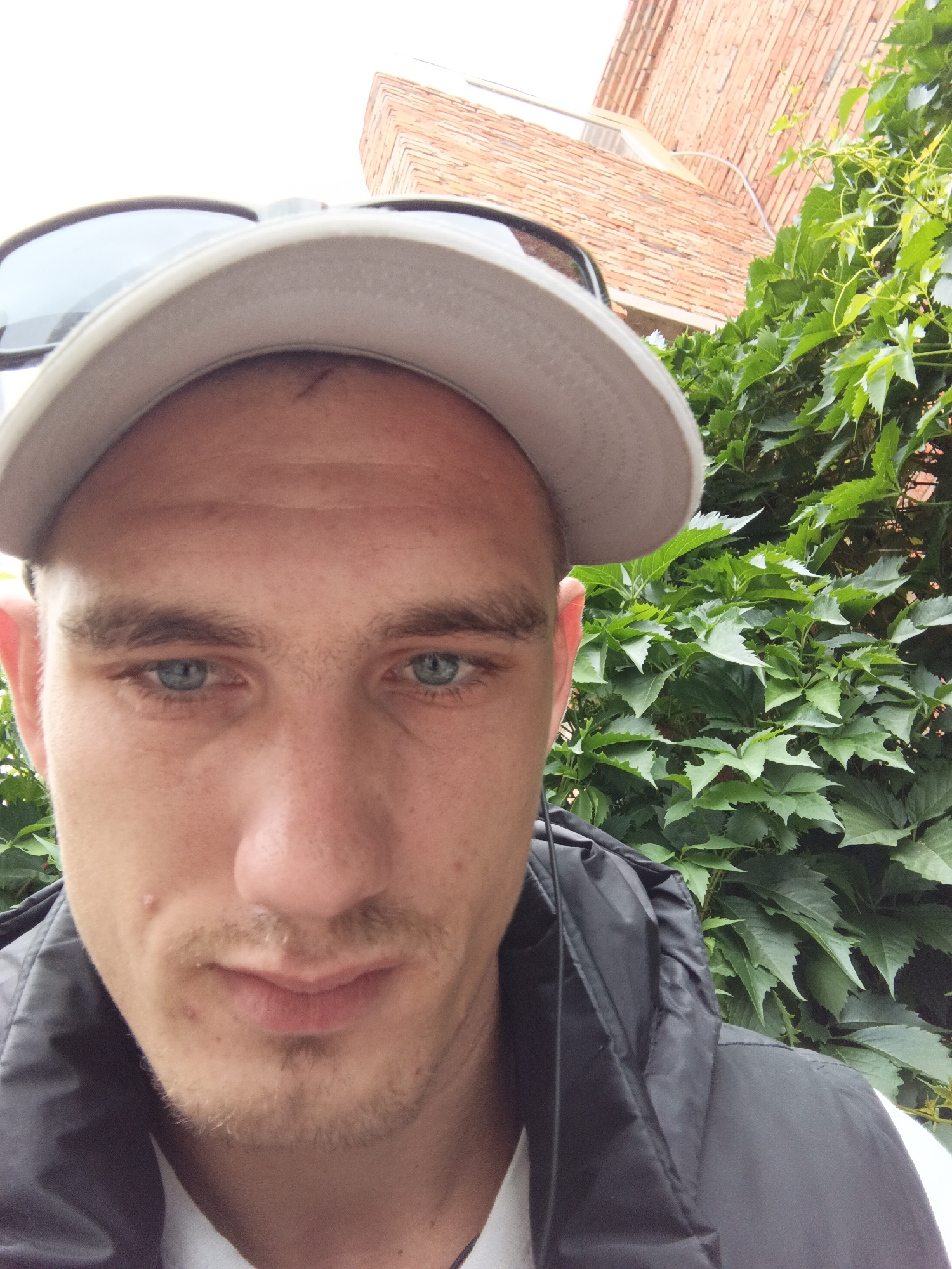 Close-up outdoor selfie, gray cap and black hoodie.