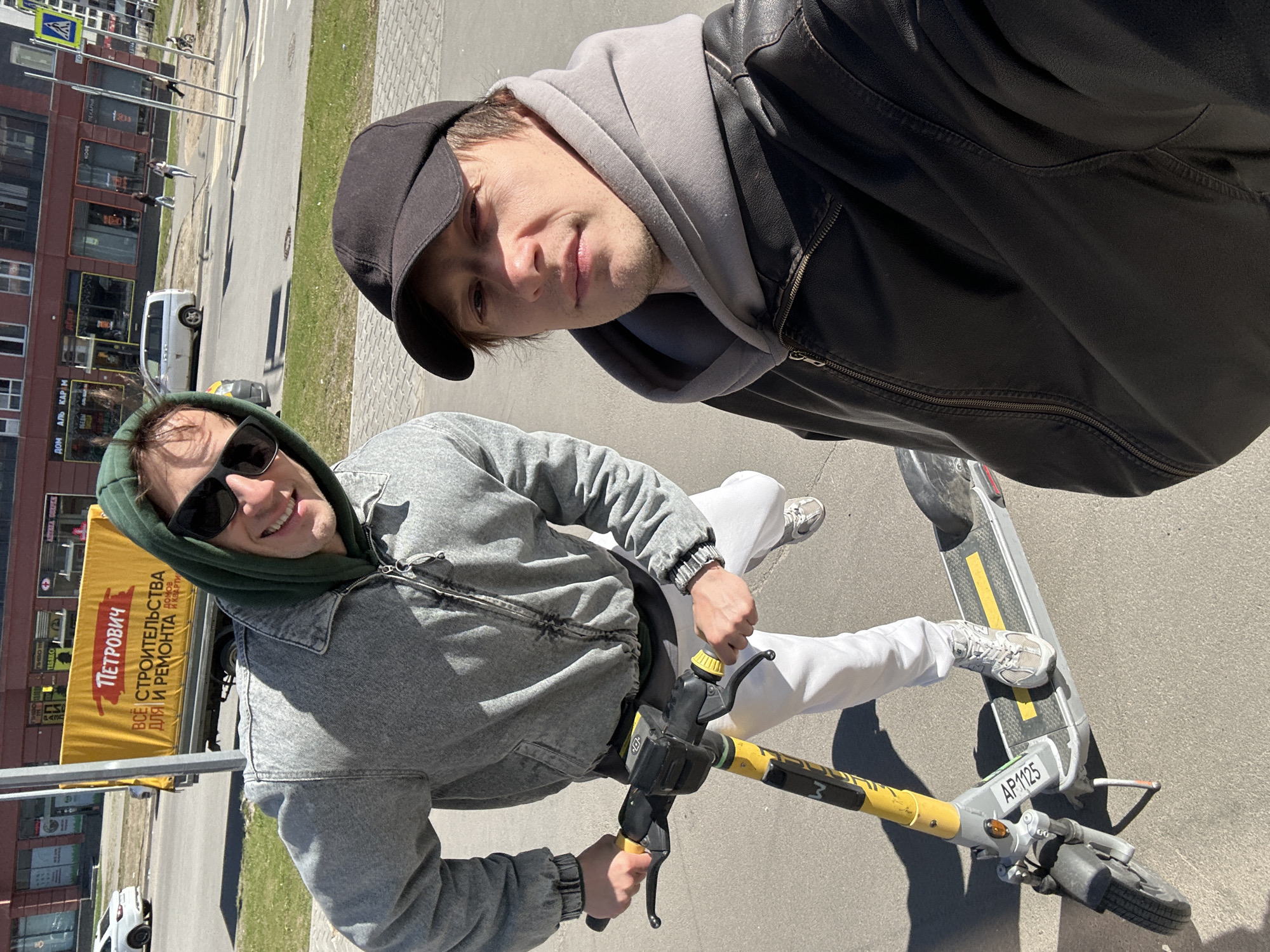 Two men take selfie while riding electric scooter in Murino