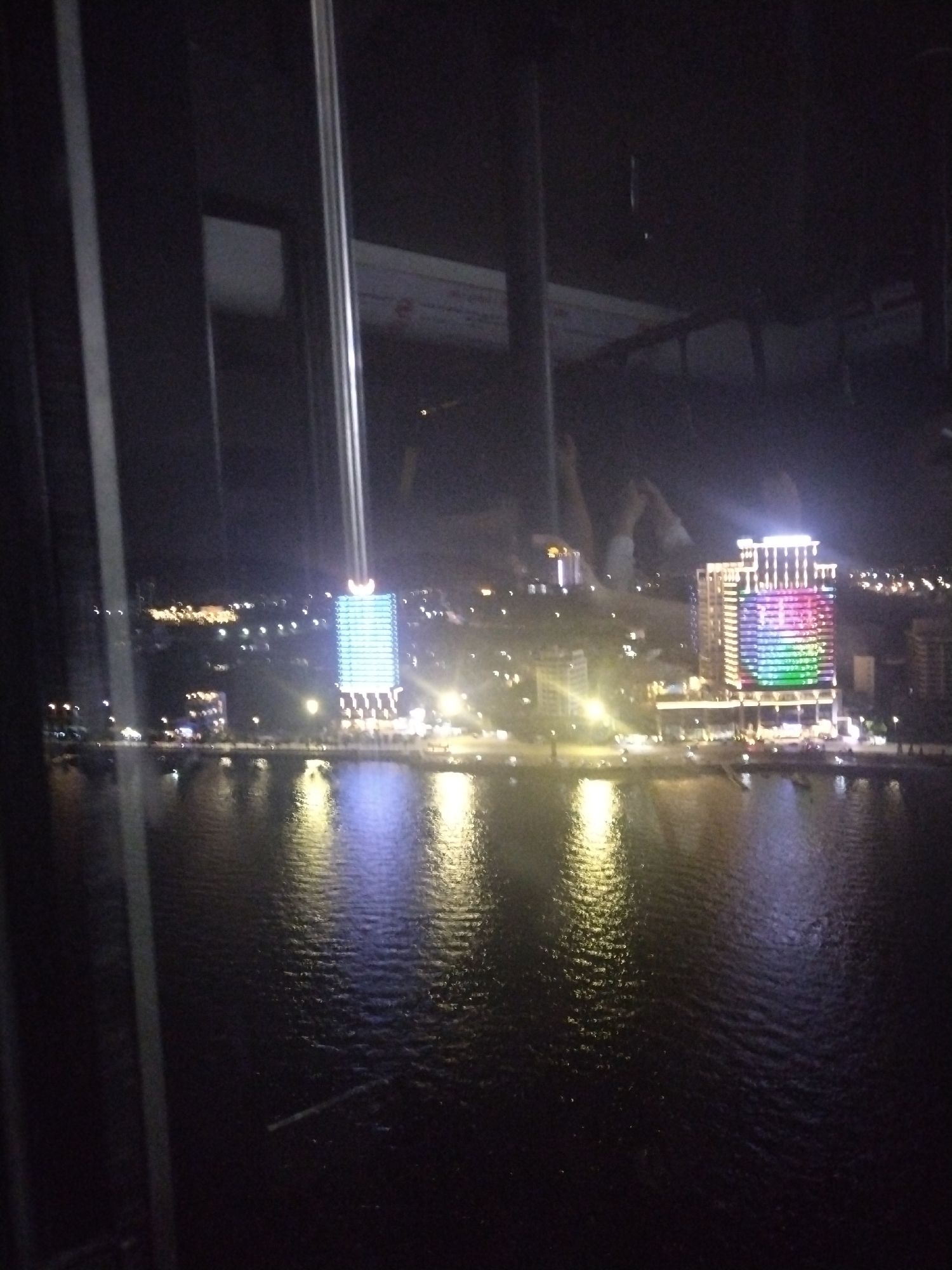 Nighttime cityscape reflection captured through window at undisclosed location