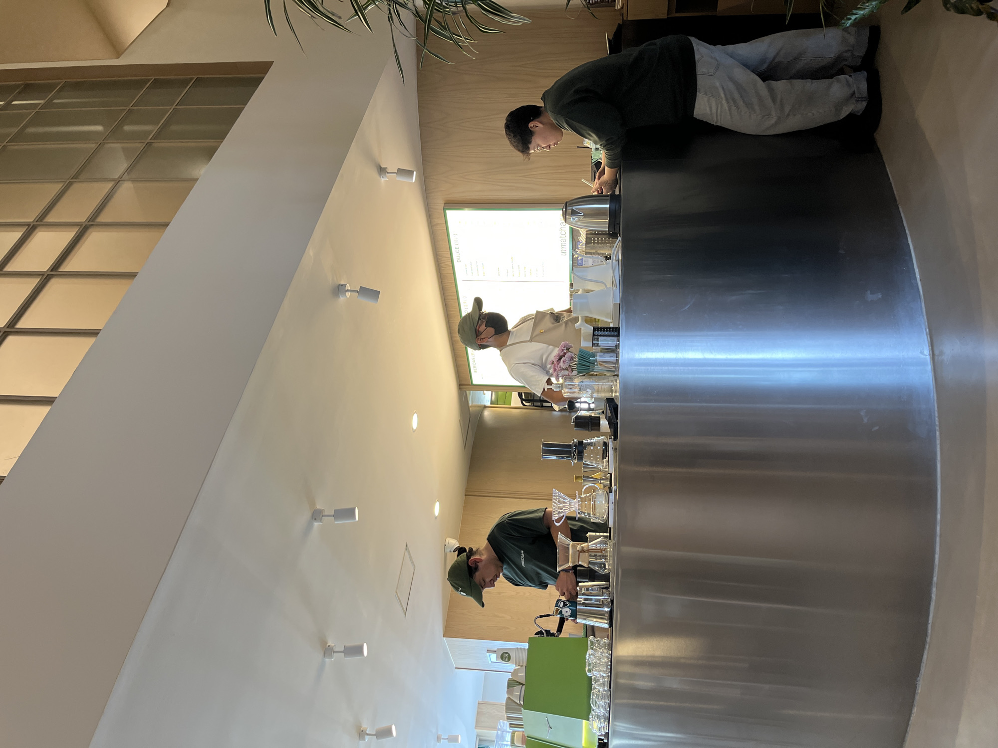 Three people behind steel counter at unknown business